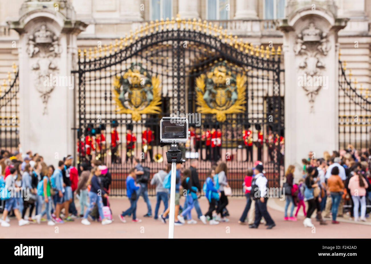 Touristen-Warteschlange, beobachten Sie die Wachablösung am Buckingham Palace, London, UK, mit einer Go pro Kamera auf einem Selfie Stick im Vordergrund. Stockfoto
