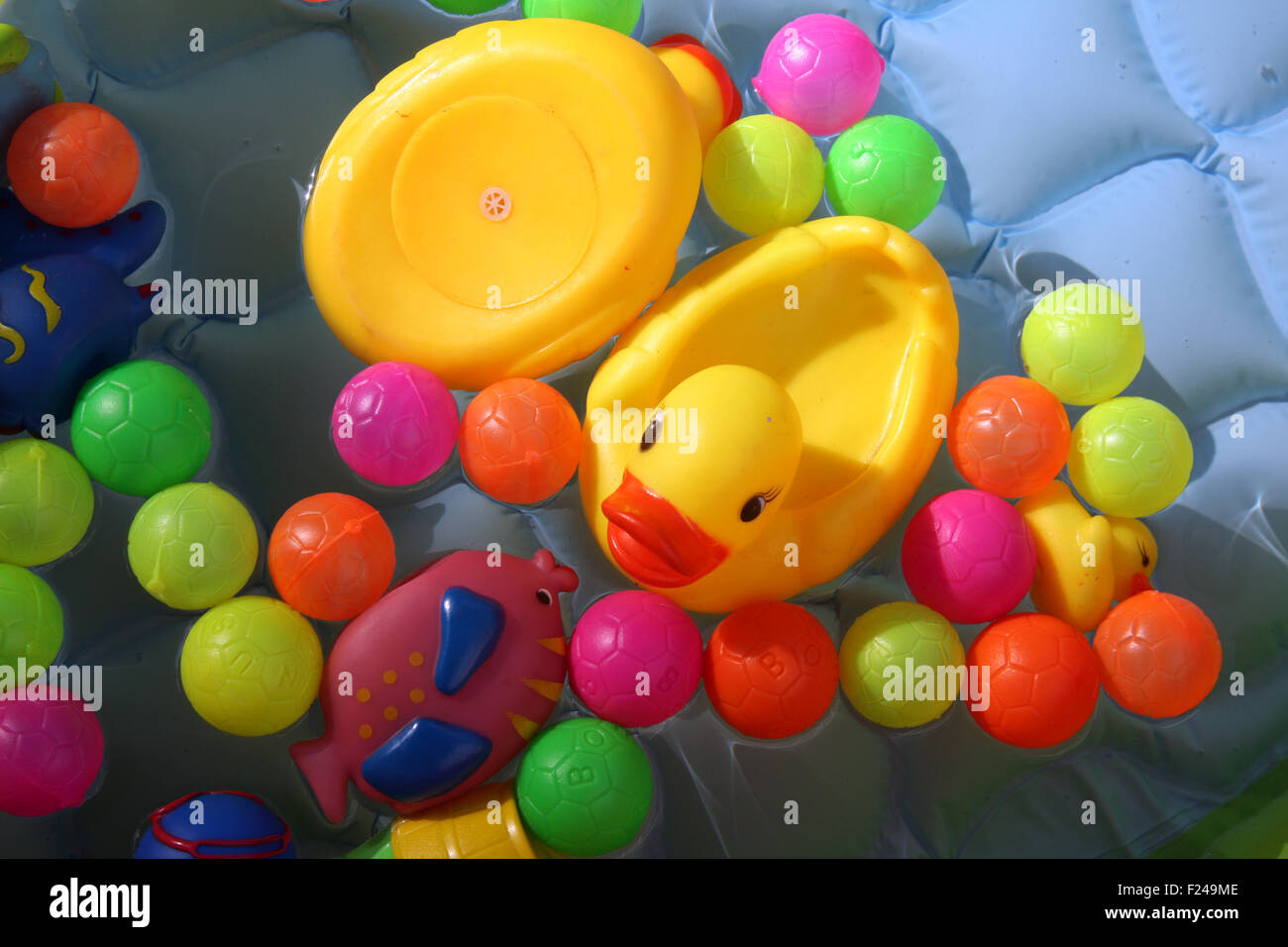 Eine gelbe Baby Ente Spielzeug im Wasser zusammen mit bunten Kugeln in einen Baby-pool Stockfoto