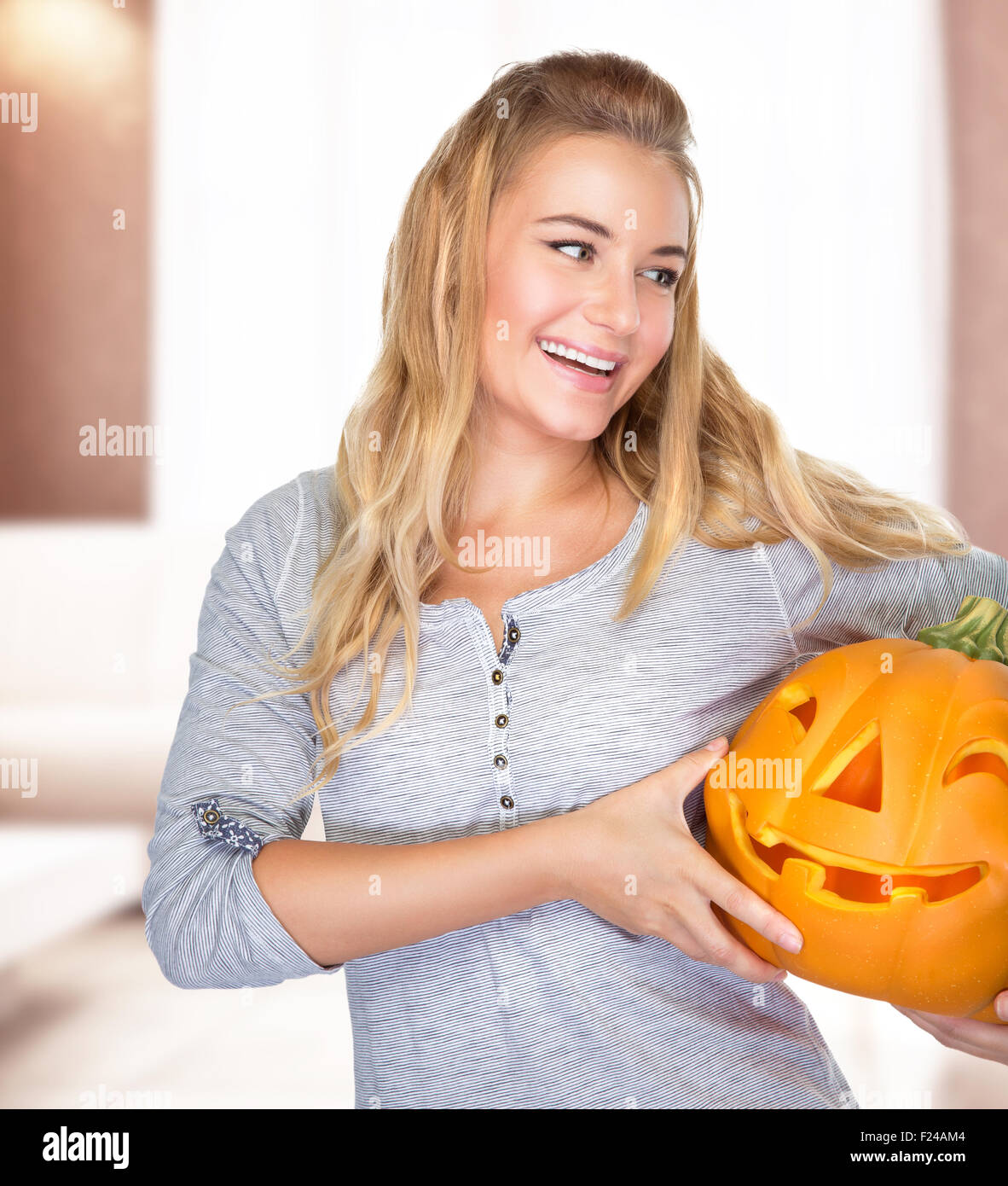 Glückliche Frau auf Halloween-Party zu Hause, in Händen hält geschnitzten Kürbis Gesicht genießen traditionelle Herbstferien Stockfoto