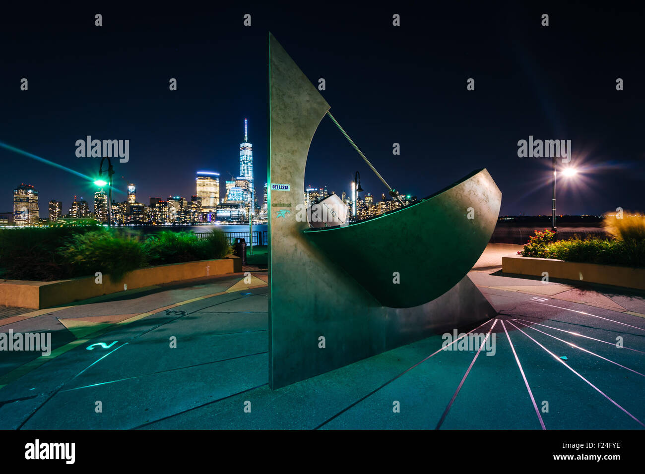 Sonnenuhr und Blick auf die Skyline von Lower Manhattan in der Nacht, in Jersey City, New Jersey. Stockfoto