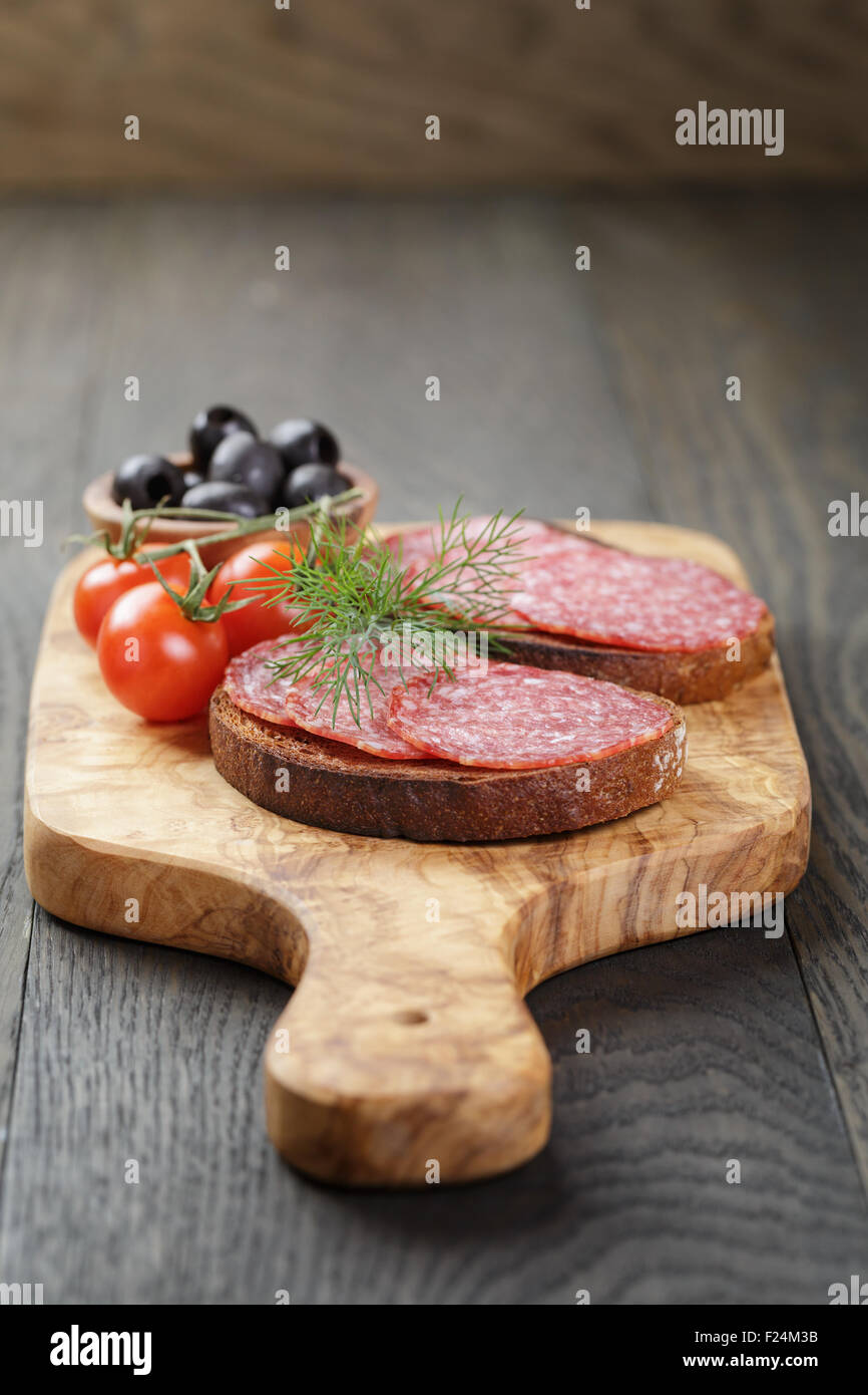 Roggen-Sandwich mit Salami und Tomaten auf Holztisch Stockfoto