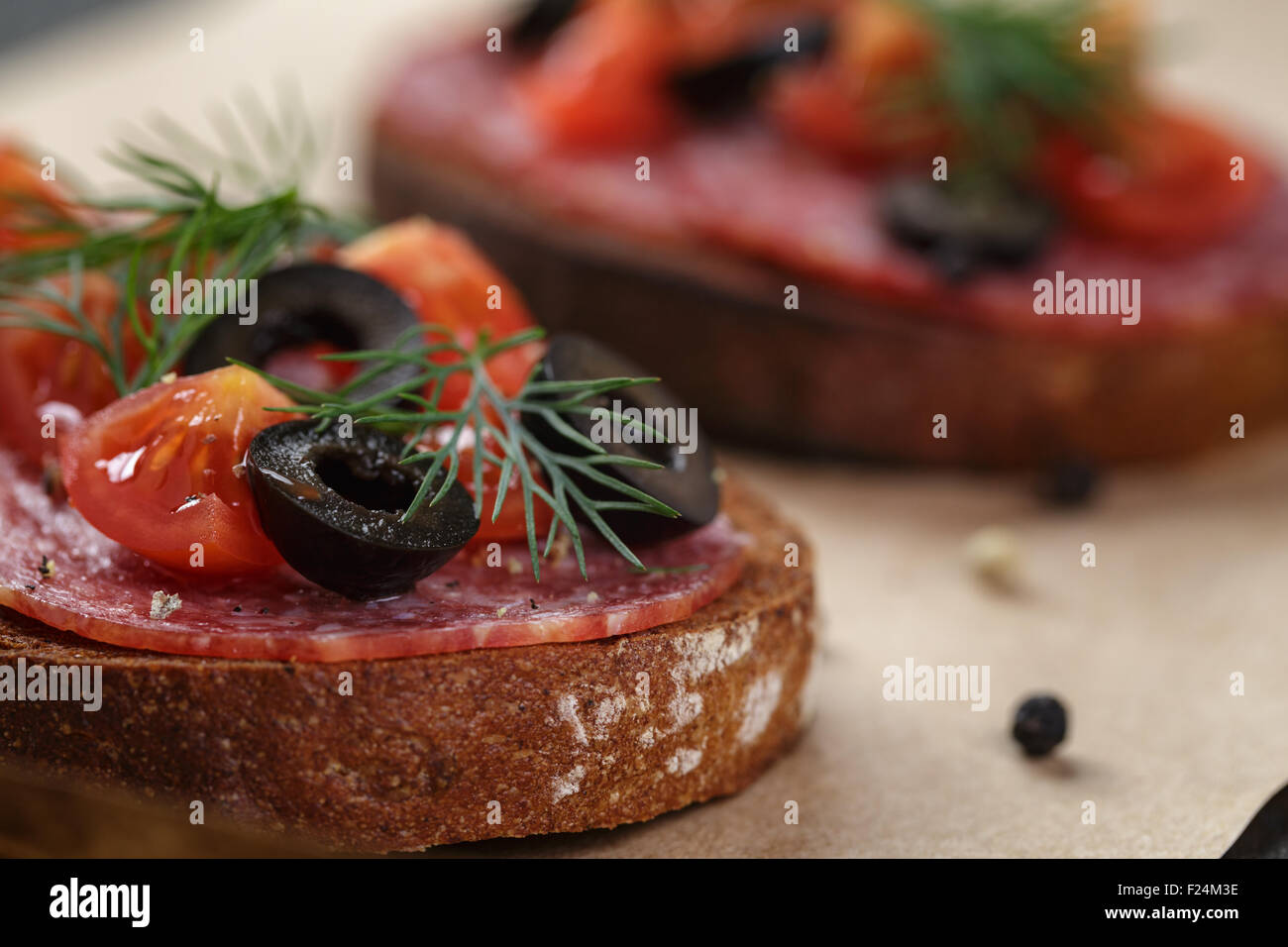 Roggen-Sandwich mit Salami und Tomaten auf Holztisch Stockfoto