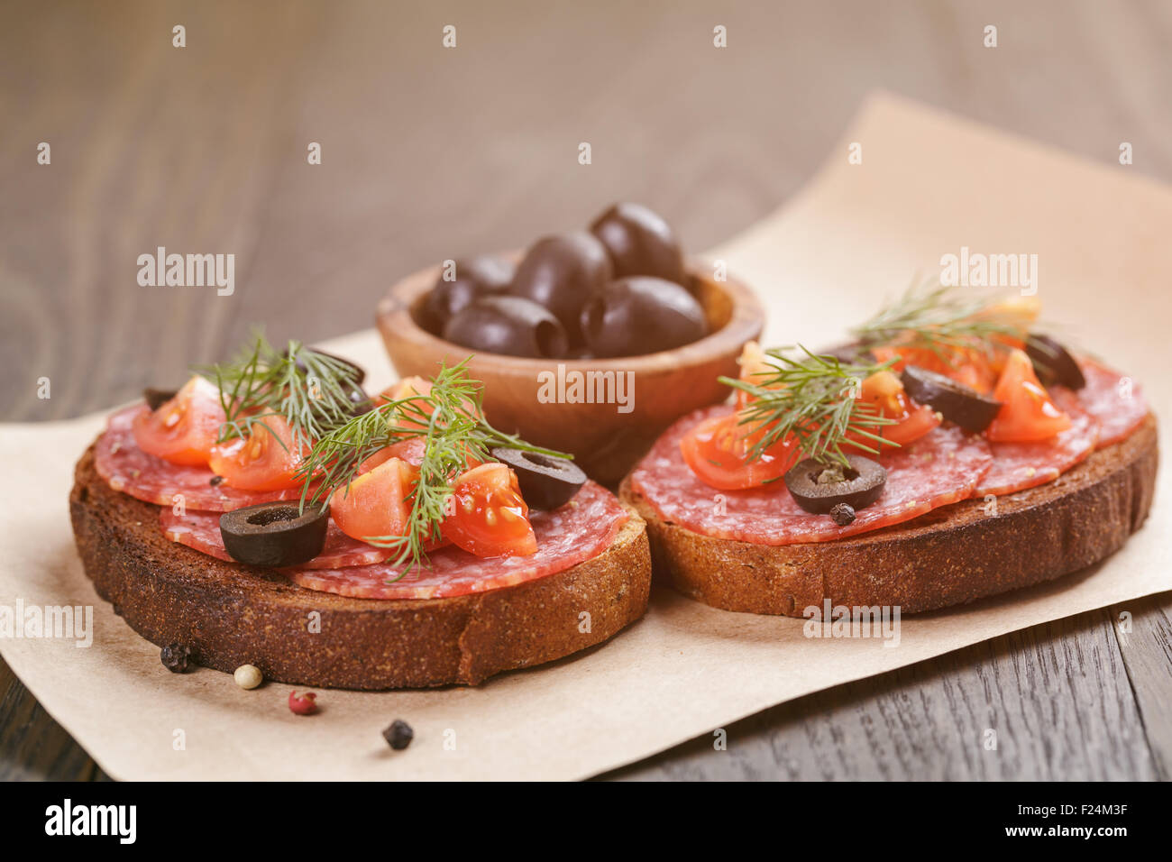 Roggen-Sandwich mit Salami und Tomaten auf Holztisch Stockfoto