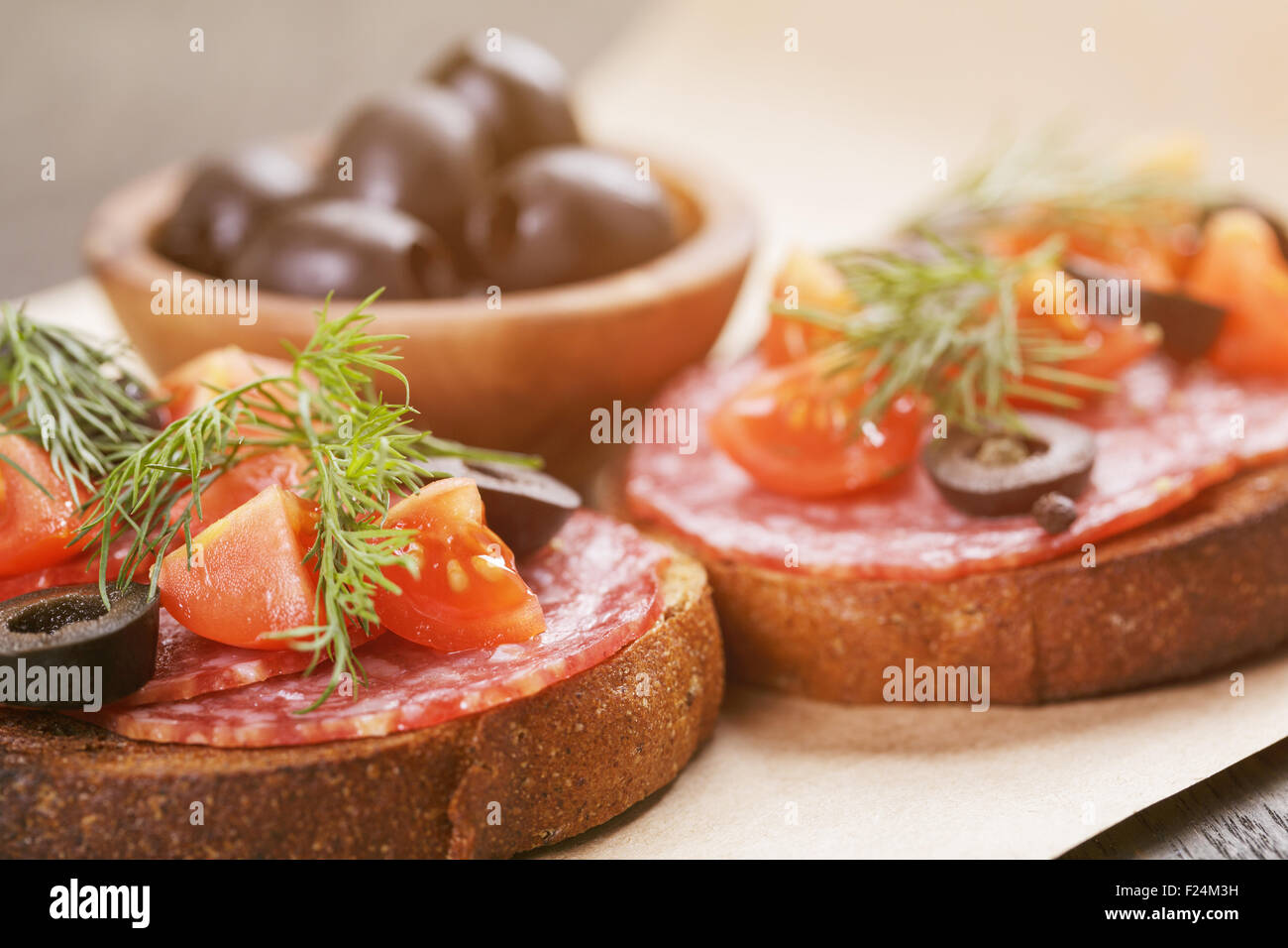 Roggen-Sandwich mit Salami und Tomaten auf Holztisch Stockfoto