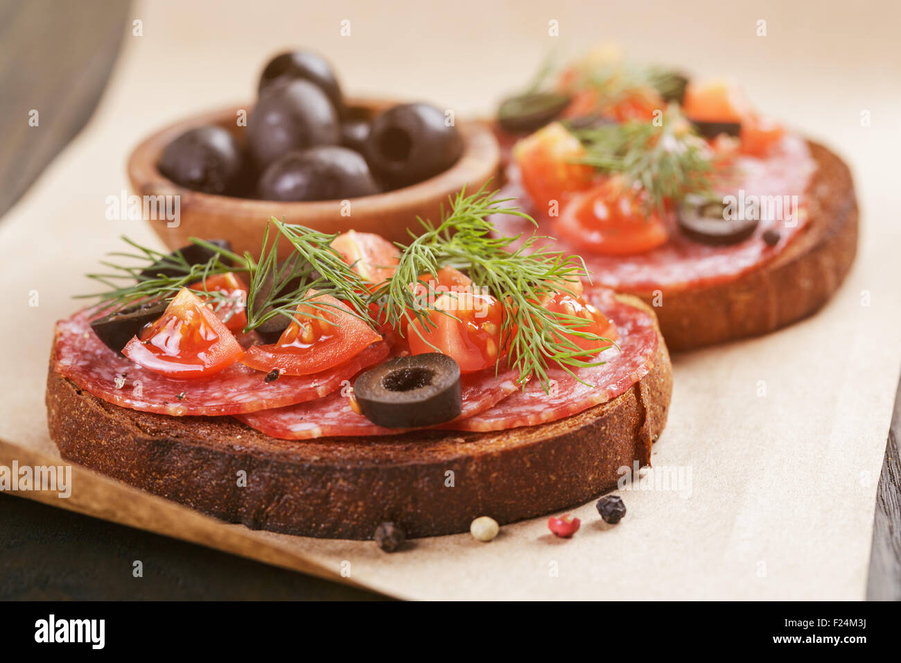 Roggen-Sandwich mit Salami und Tomaten auf Holztisch Stockfoto