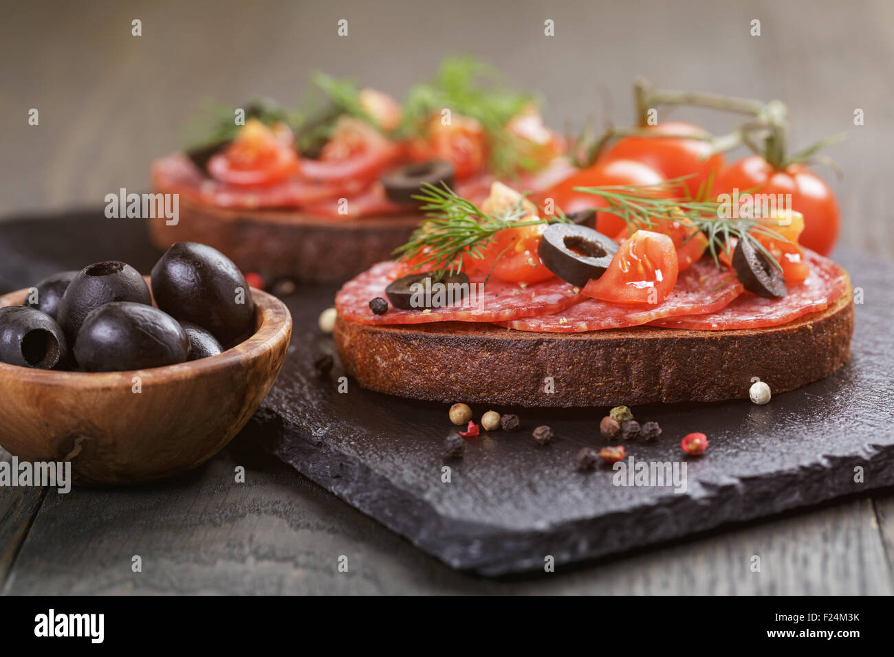 Roggen-Sandwich mit Salami und Tomaten auf Holztisch Stockfoto