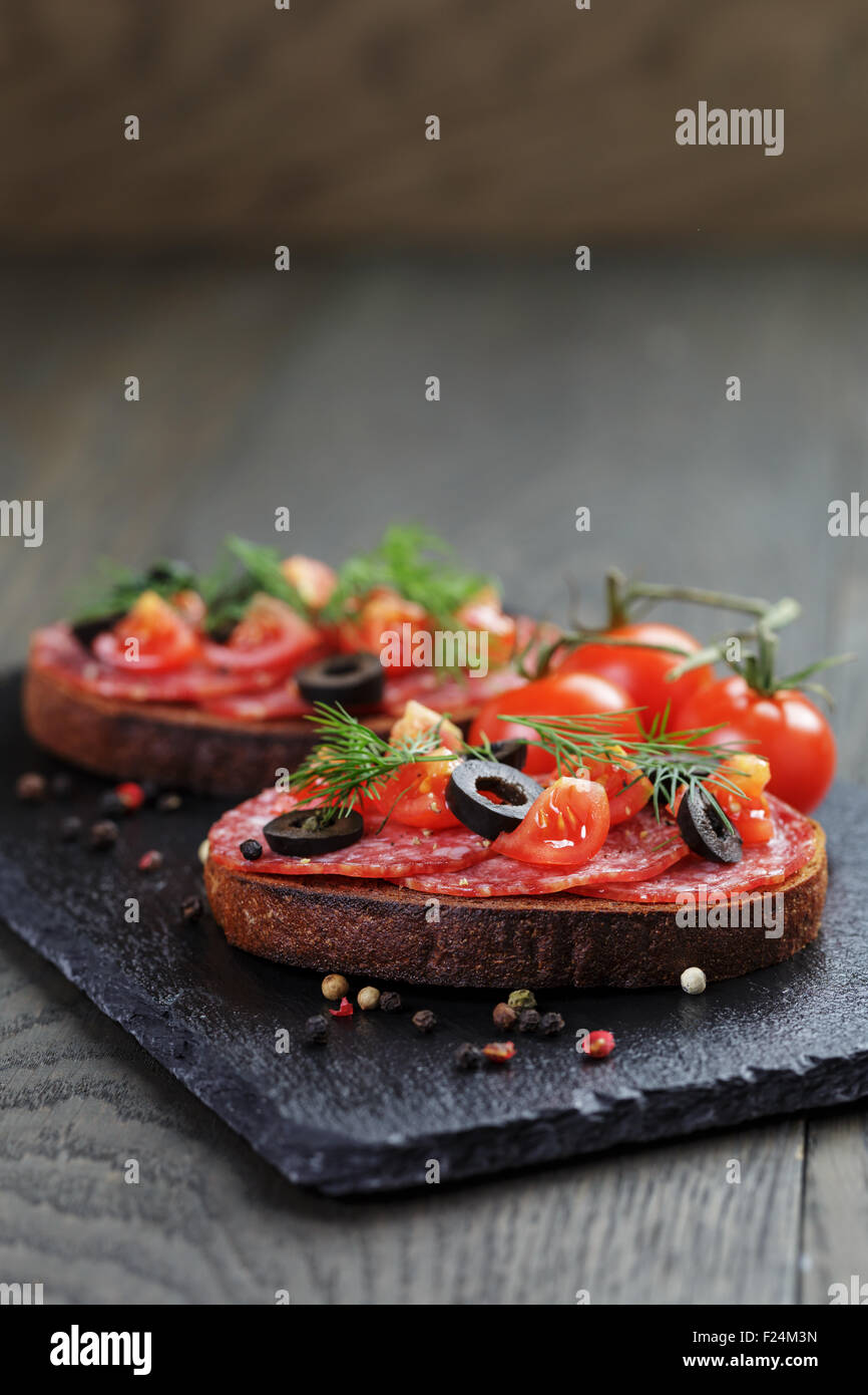 Roggen-Sandwich mit Salami und Tomaten auf Holztisch Stockfoto
