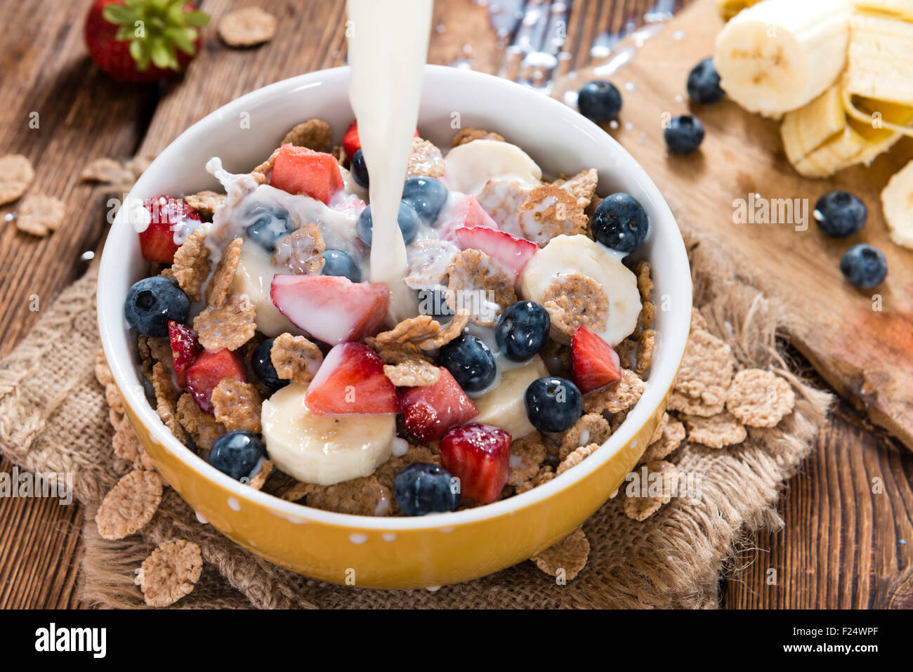 Cornflakes mit frischen Früchten und Milch auf einem Holztisch Stockfoto