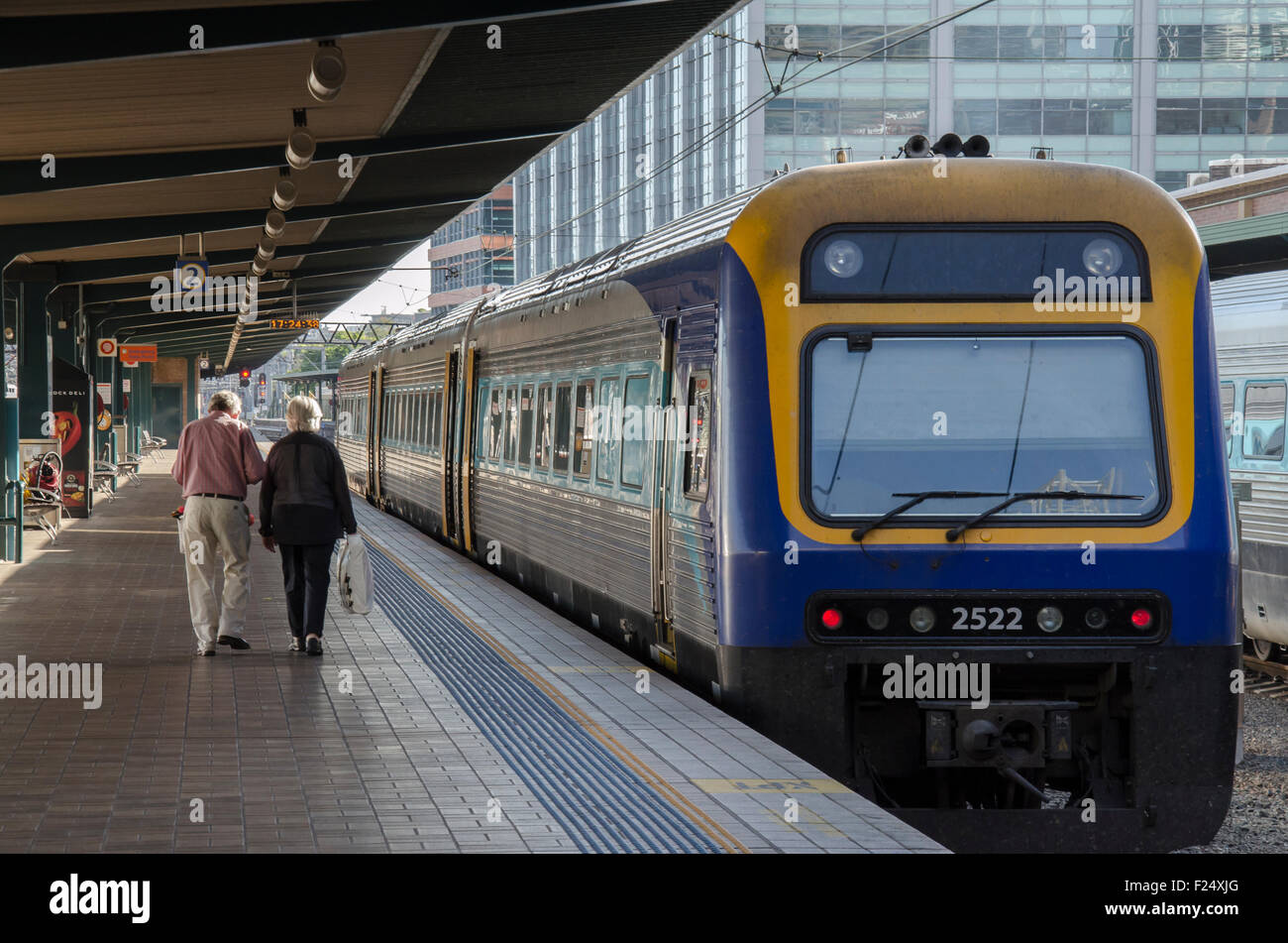 Zwei ältere Menschen gehen eine Bahnsteigeplattform hinunter in Richtung eines wartenden Zuges. Der Zug ist ein Diesel Endeavour Klasse Lokomotive Land Service aus Sydney. Stockfoto