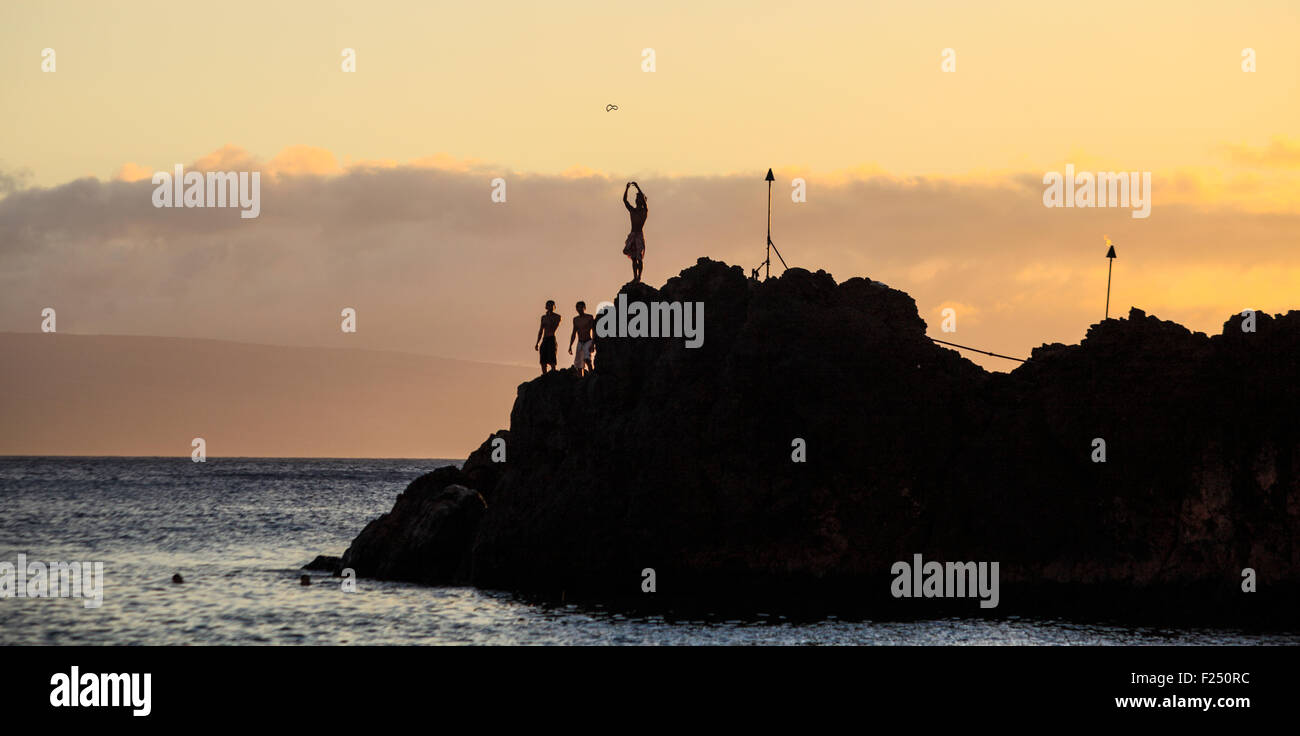 Klippenspringer wirft Lei während Sonnenuntergang Fackel-Zeremonie in Black Rock am Kaanapali Beach auf Maui Stockfoto