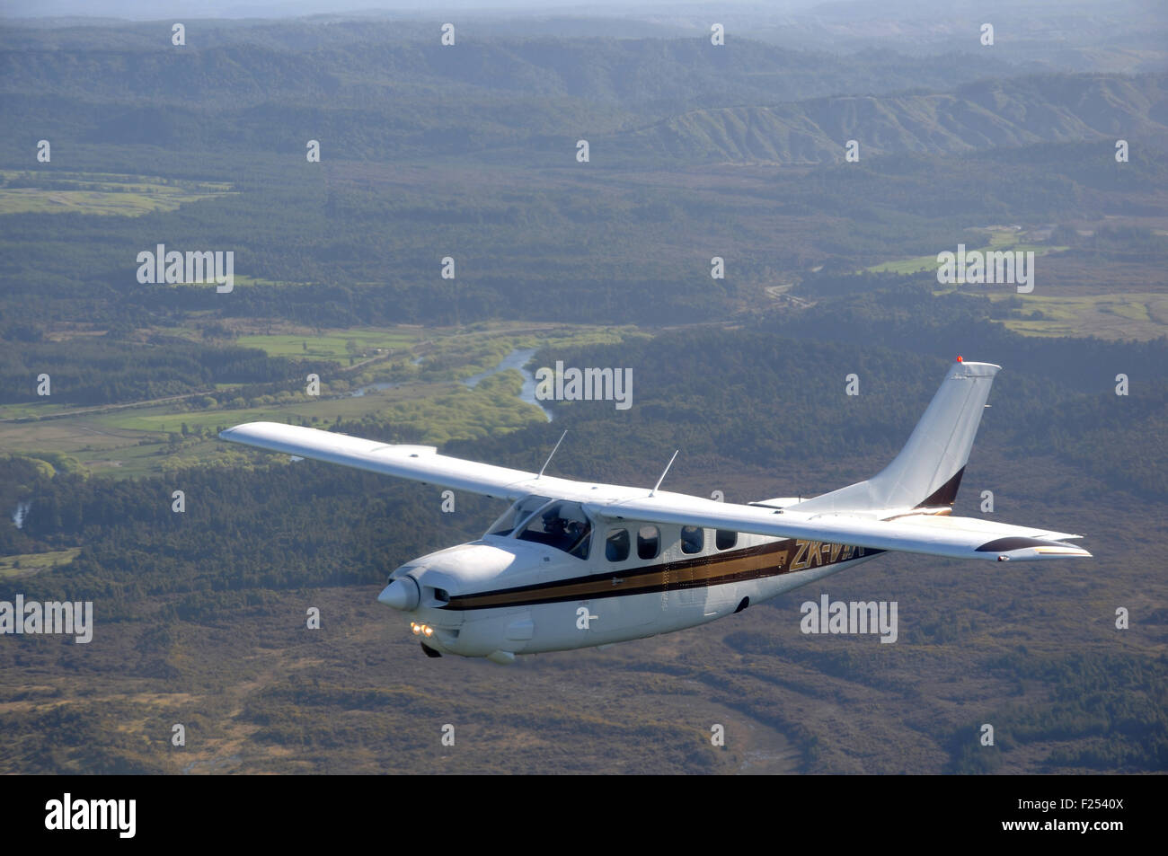 Ein unter Druck stehendes Cessna 210 fliegt über der malerischen Westküste von Neuseeland Stockfoto