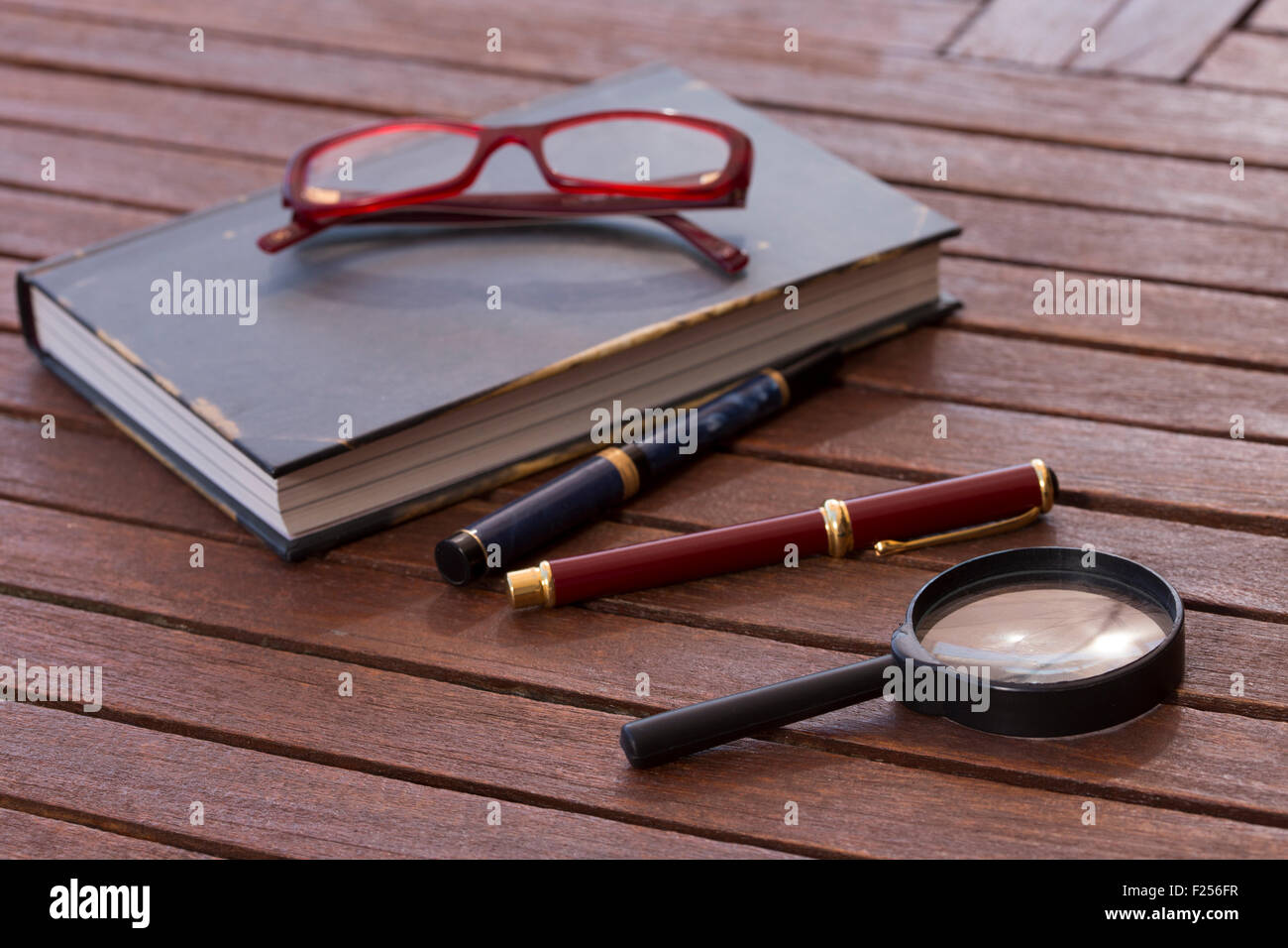 Buch und Brille und Stifte auf einem Tisch Stockfoto