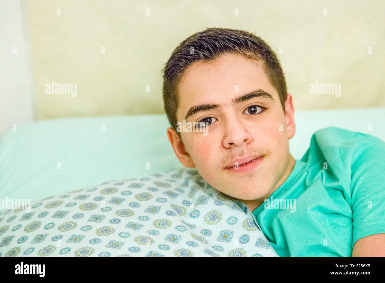 Kaukasische Teen Boy mit geschweiften Klammern umarmt Kissen im Bett Stockfoto