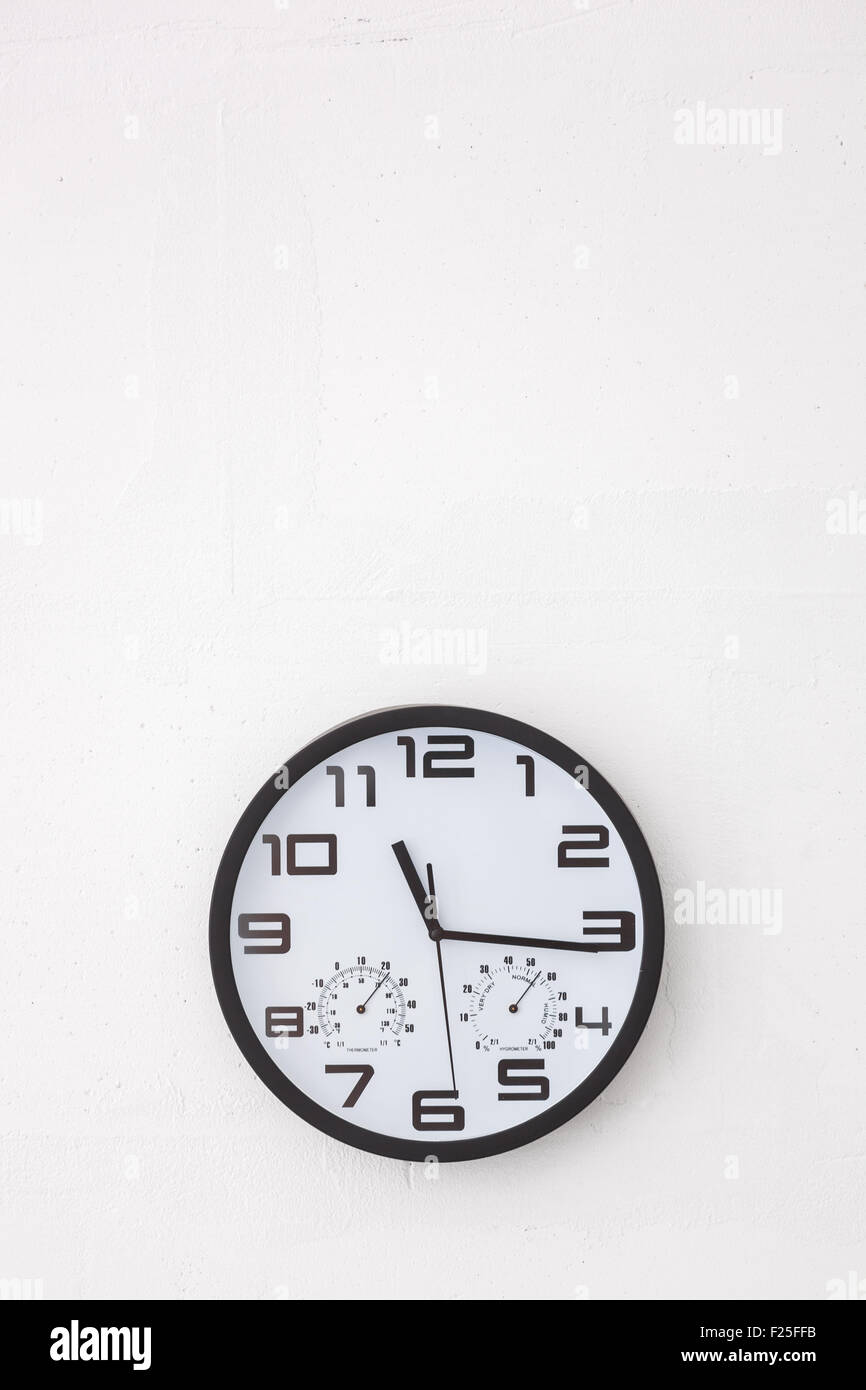 Große schwarze rund um die Uhr auf weißen Wand. Stockfoto