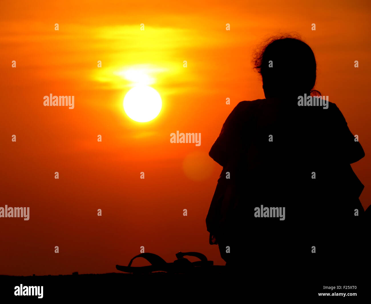 Eine Silhouette der einsame Frau sitzt alleine den Sonnenuntergang beobachten. Stockfoto