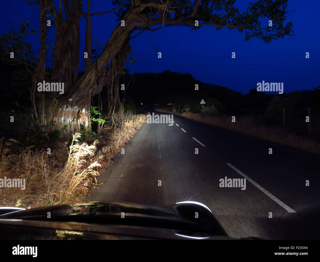 Ein Auto fährt nachts auf einer einsamen indische Autobahn in der Landschaft. Stockfoto