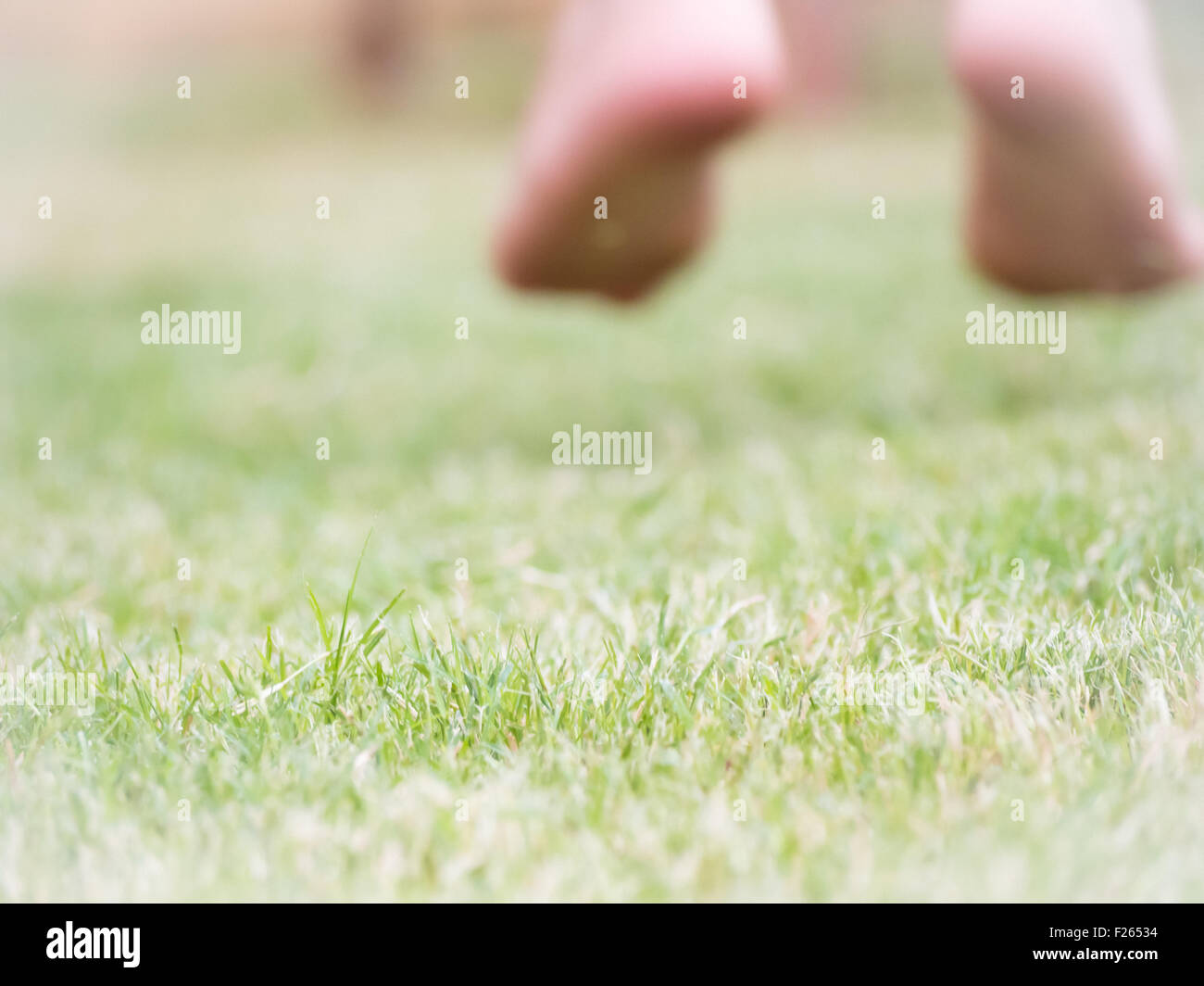 springen Sie auf dem Rasen nach dem Glück. Bild mit Füßen von Kid, die direkt auf dem Rasen zu verwischen. Konzept des Glücks Stockfoto