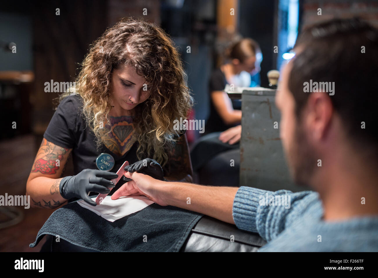 München, Deutschland. 3. Sep 2015. Kosmetikerin Caro gibt Kunde Anys eine Maniküre im Nagelstudio "Hammer & Nagel" in München, 3. September 2015. Der Salon ist die erste Nagelstudio für Männer in Deutschland. Foto: Matthias Balk/Dpa/Alamy Live News Stockfoto