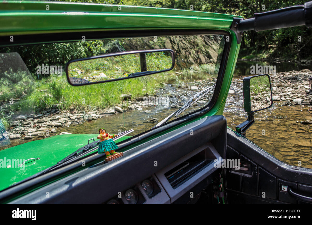 fahren durch einen Bach in einem Jeep mit einem Hula-Mädchen im dashboard Stockfoto