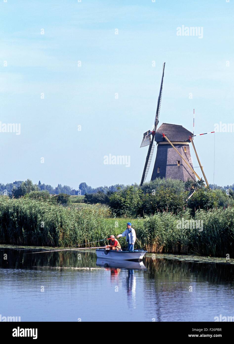 Zwei lokale Männer Angeln auf dem Deich wind eine Windmühle auf der Rückseite, Kinderdijk, Holland, Niederlande, Europa. Stockfoto