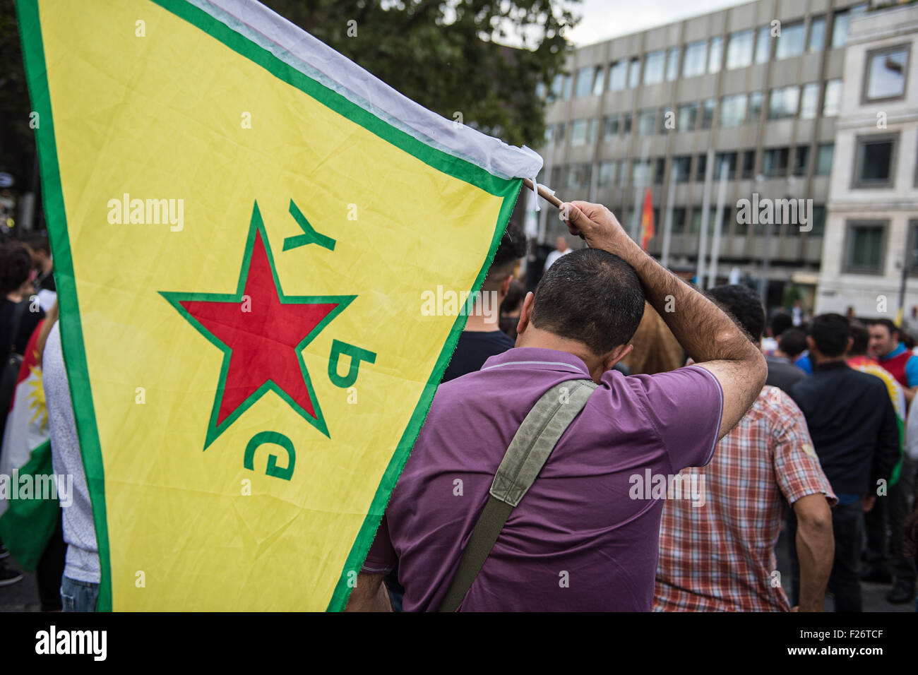 Ein Teilnehmer an einer Kundgebung gegen die Politik der türkischen Regierung, trägt eine Flagge des so genannten "Peoples Schutz Einheiten" (YPG), die wichtigsten bewaffneten Dienst der kurdischen Supreme Committee, der Regierung der Syrisch-Kurdistan, wie sie marschiert durch die Straßen von Stuttgart, Deutschland, 12. September 2015. Einige 2.000 Kurden und der türkischen Regierung, die Kritiker auf die Straße gingen, um die eskalierende Spannung in ihrem Land zu protestieren, nachdem eine Welle von Luftangriffen gegen die kurdische Arbeiterpartei (PKK) Ziele im Nordirak Türkei durchgeführt. Foto: Wolfram Kastl/dpa Stockfoto