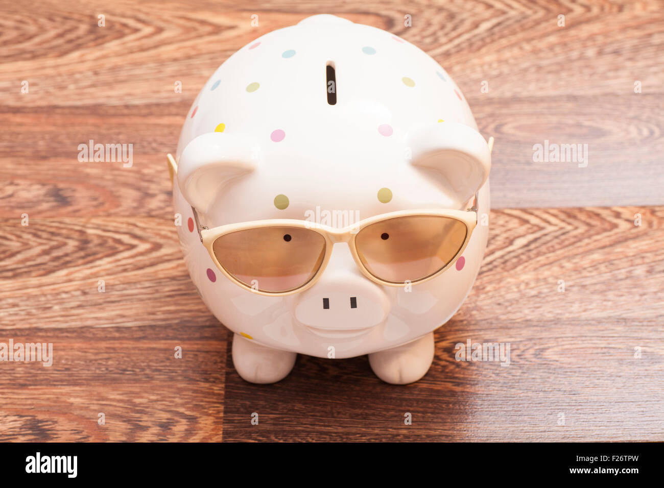 Sparschwein mit Sonnenbrille auf hölzernen Hintergrund Stockfoto