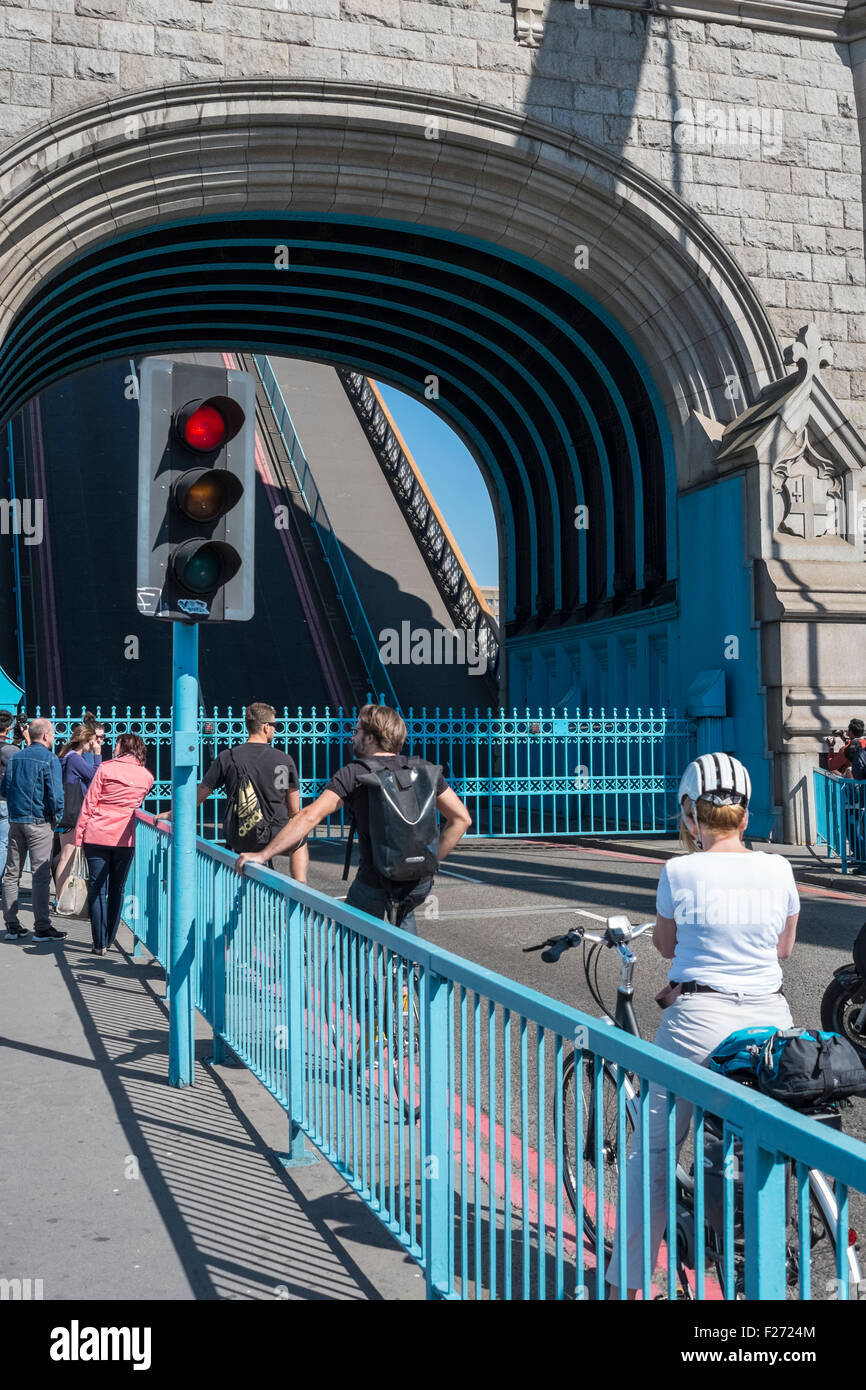 Verkehr und Fußgänger warten auf Tower Bridge Brücke aufgezogen ist, London, England UK Stockfoto