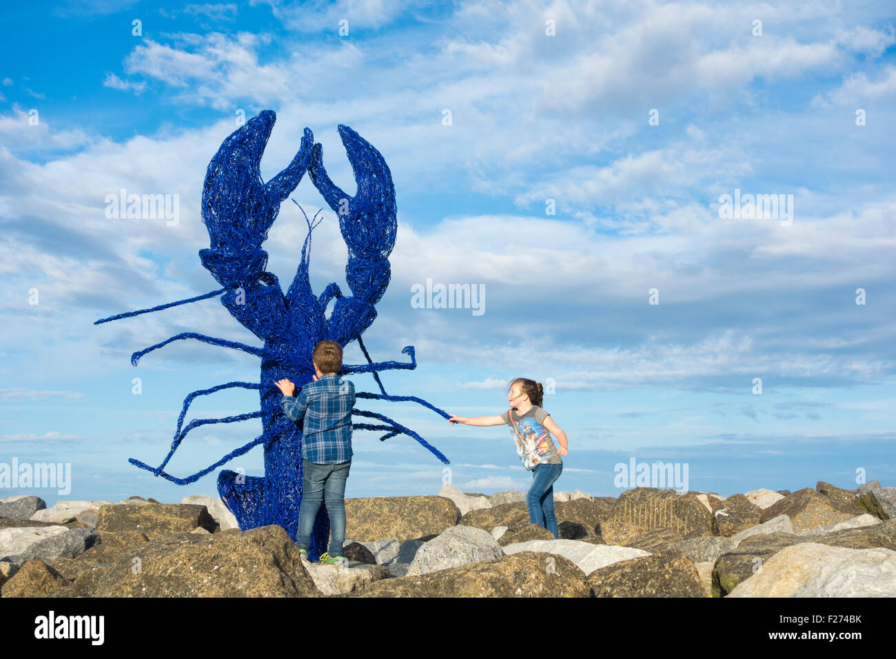 Samstag, 12. September 2015, Staithes, North Yorkshire, England, Vereinigtes Königreich. Wetter: Ein echter Autumnal fühlen, das Wetter wie Starkregen und Donner gefolgt von Sonne dann klar Abend Himmel am Samstag während des Festivals Staithes Art an der Tagesordnung waren. Während das Festwochenende öffnen 130 Künstlern und neunzig Galerien ihre Studios/Häuser für die Öffentlichkeit und Käufer. Bild: Kinder auf der Hafenmauer in der Nähe von Skulptur des Riesen erstellt Hummer von Emma Stothard speziell für das Festival-Wochenende. Stockfoto