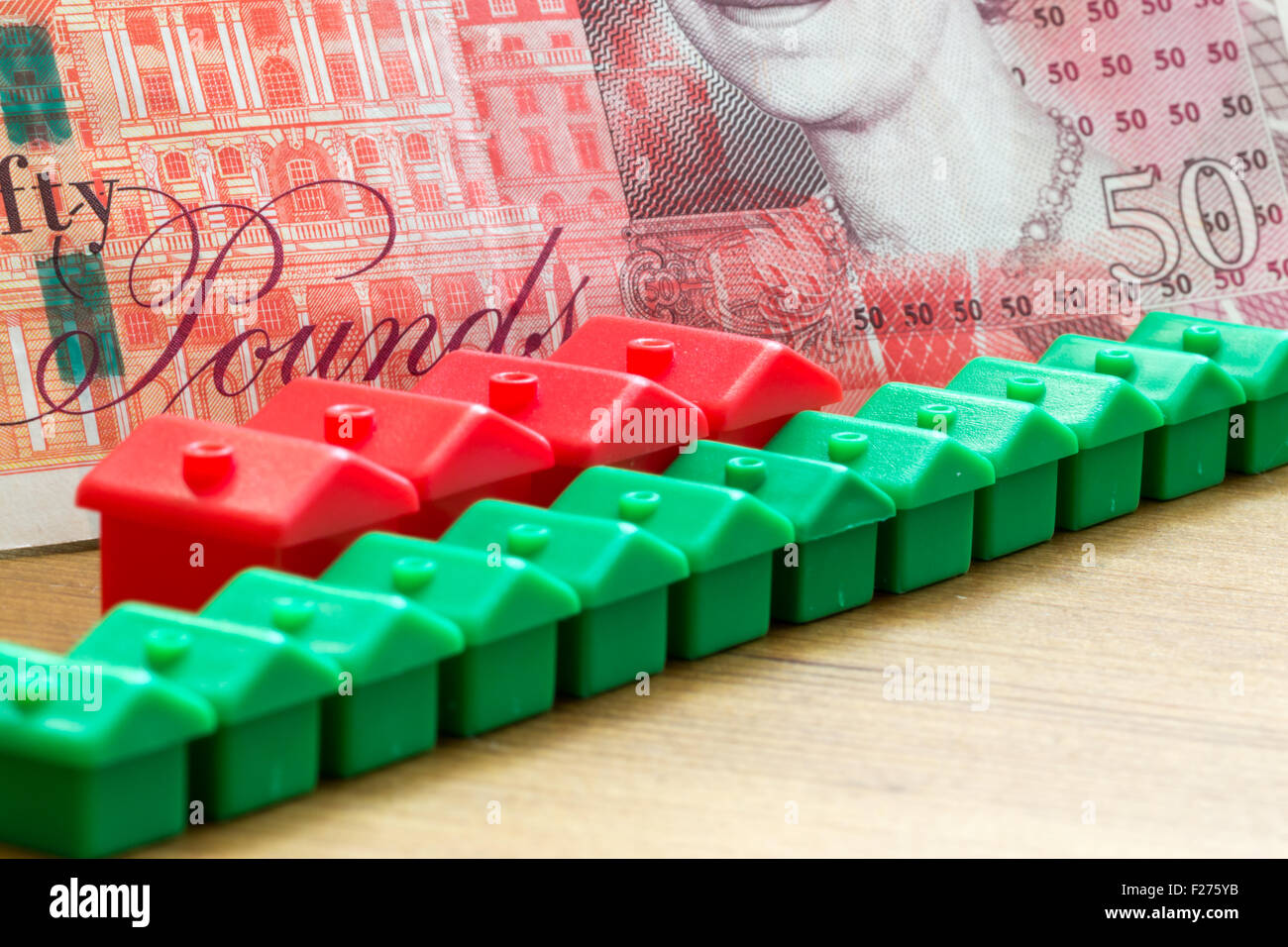 Grüne und rote Imitation Plastikmodell beherbergt Form einer dynamischen diagonalen Reihe mit einer einzigen britischen fünfzig Pfund Banknote in den Rücken Stockfoto