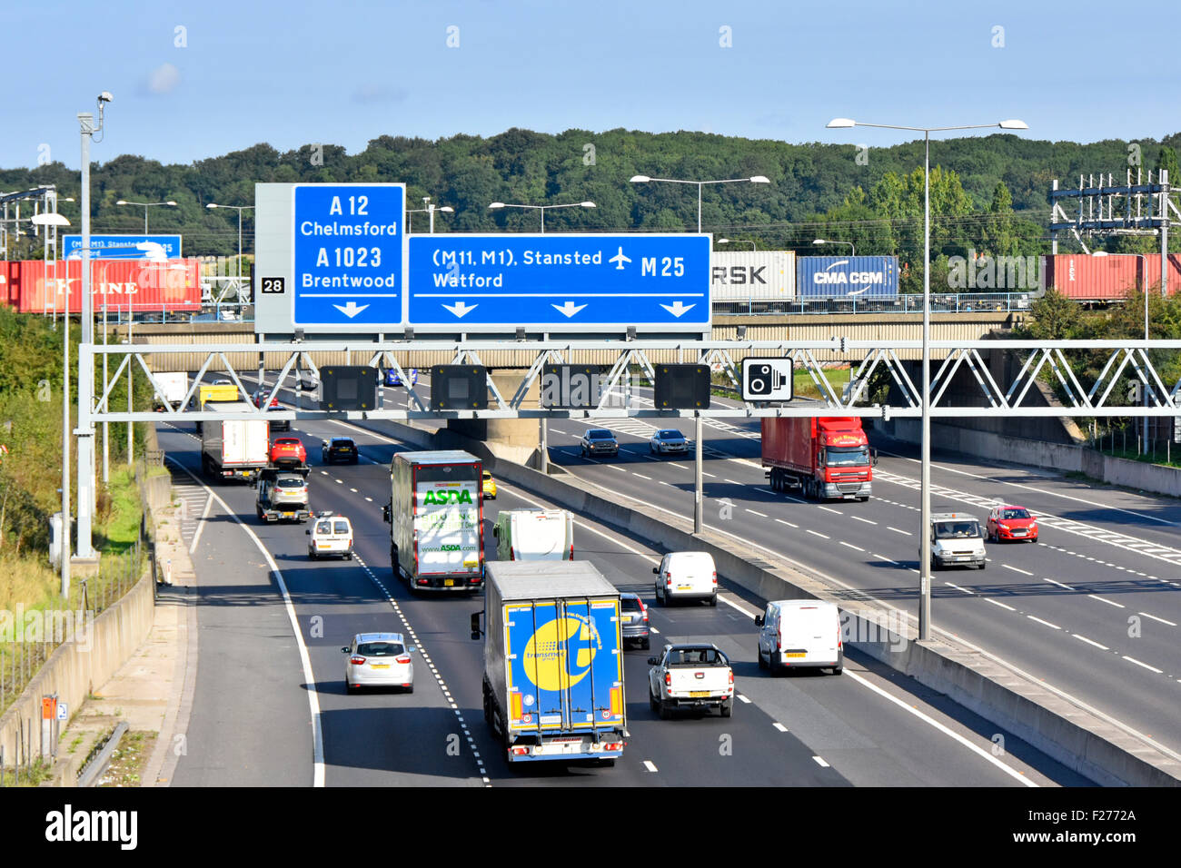 Transportmöglichkeiten M25 Autobahn Eisenbahnbrücke & Container Güterzug über Straße Verkehr blaue Verkehrsschilder für Kreuzung 28 Brentwood Essex England UK Stockfoto
