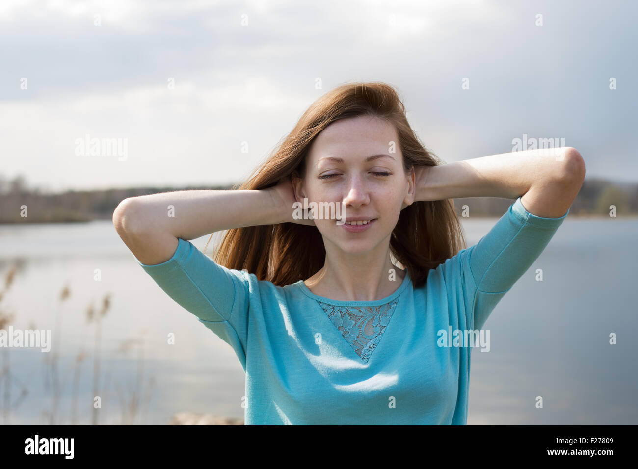 Sommersprossige fröhliches Mädchen mit geschlossenen Augen halten ihre Hände hinter ihrem Kopf Stockfoto