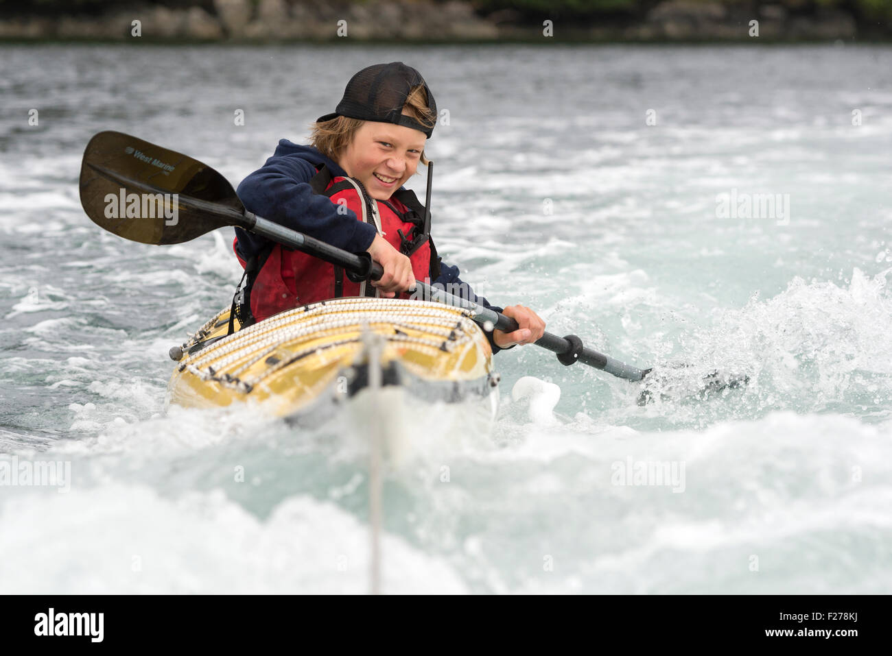 Junge im Seekajak wird von einem Motorboot in Southeast Alaska gezogen. Stockfoto
