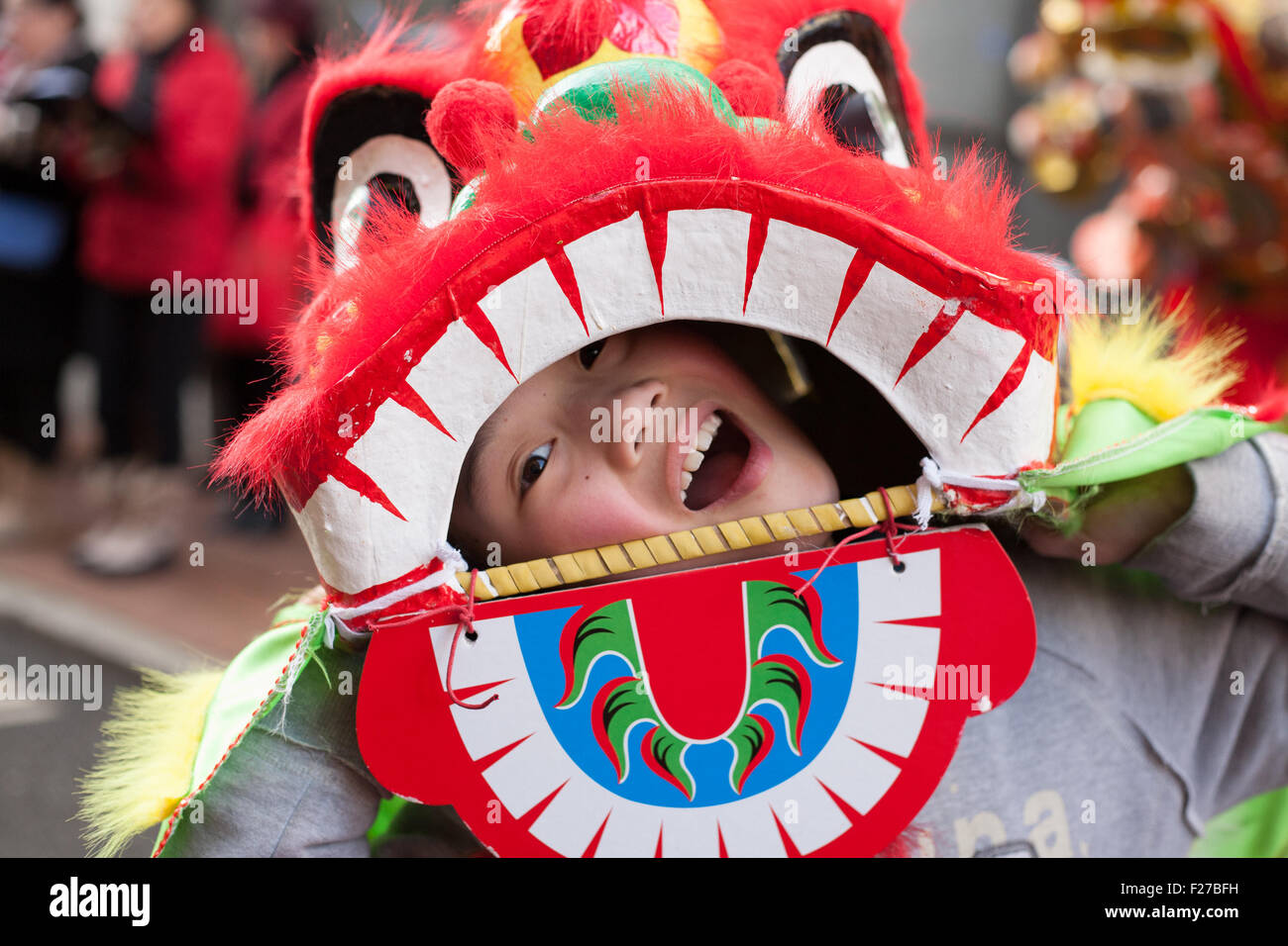 Ein Junge lächelt glücklich durch seine Drachenmaske während der Feierlichkeiten für Chinese New Year in Manchester, England. Der Tag markiert Stockfoto