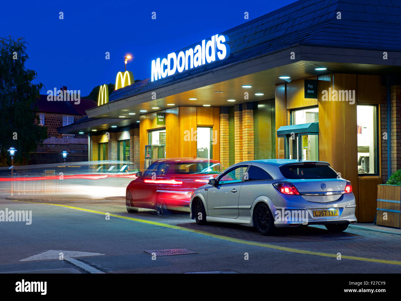 Autos im McDonald's Drive-in-Restaurant, in der Nacht, England UK Stockfoto