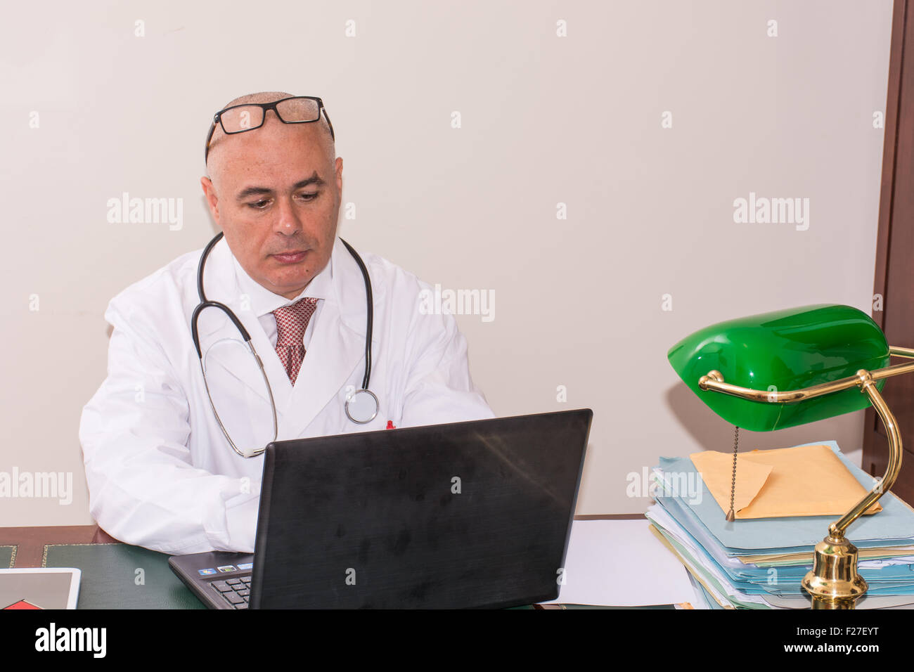 Arzt in seinem Atelier am Schreibtisch, am pc, mit Brille. Nutzen Sie neue Technologien. Er sitzt in seinem professionellen Studio bei antiken d Stockfoto