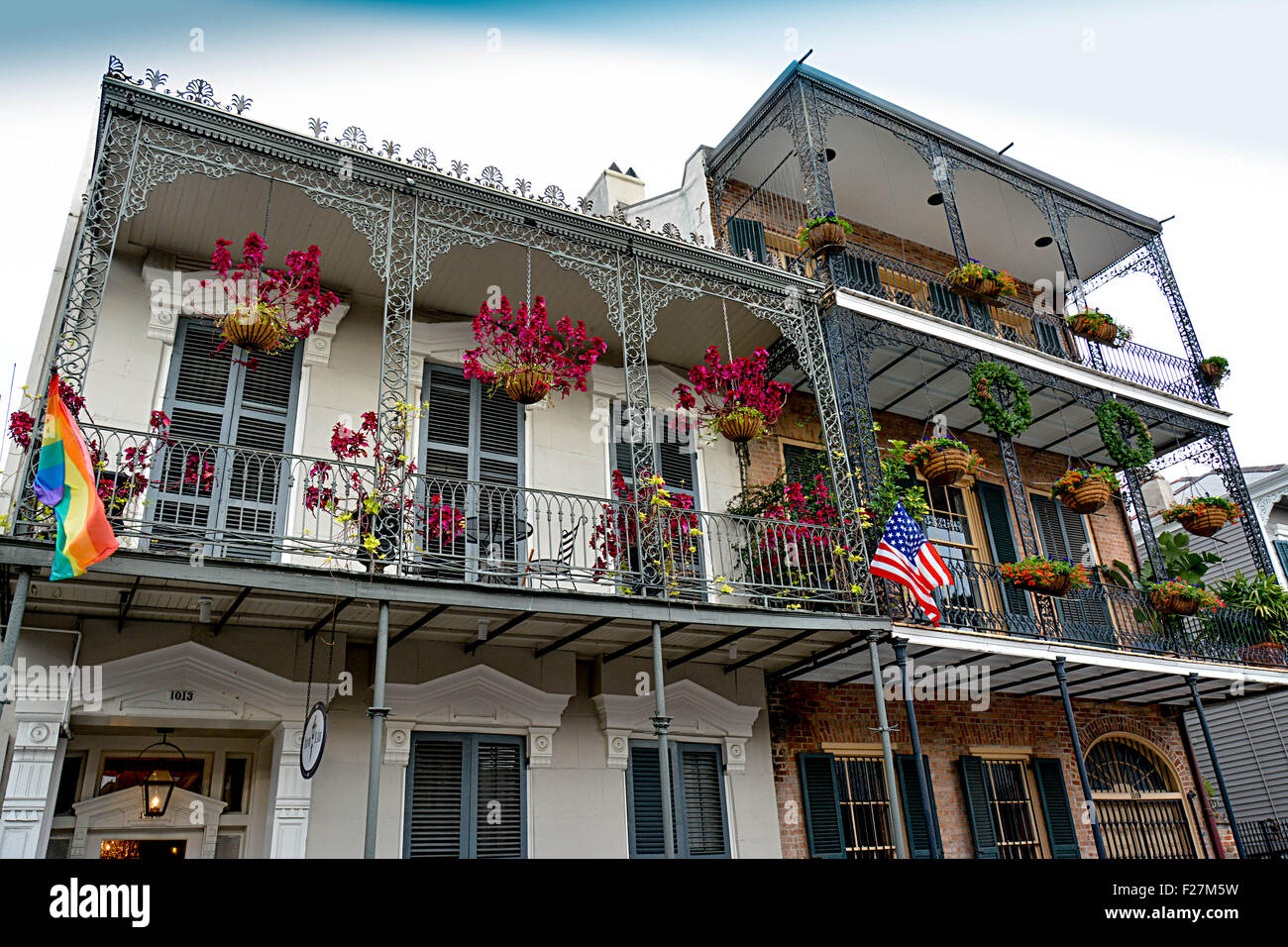 Eine Creole Stadthaus mit reich verzierten schmiedeeisernen Balkonen, hängenden Blüten und Regenbogenfahne im French Quarter von New Orleans, LA Stockfoto