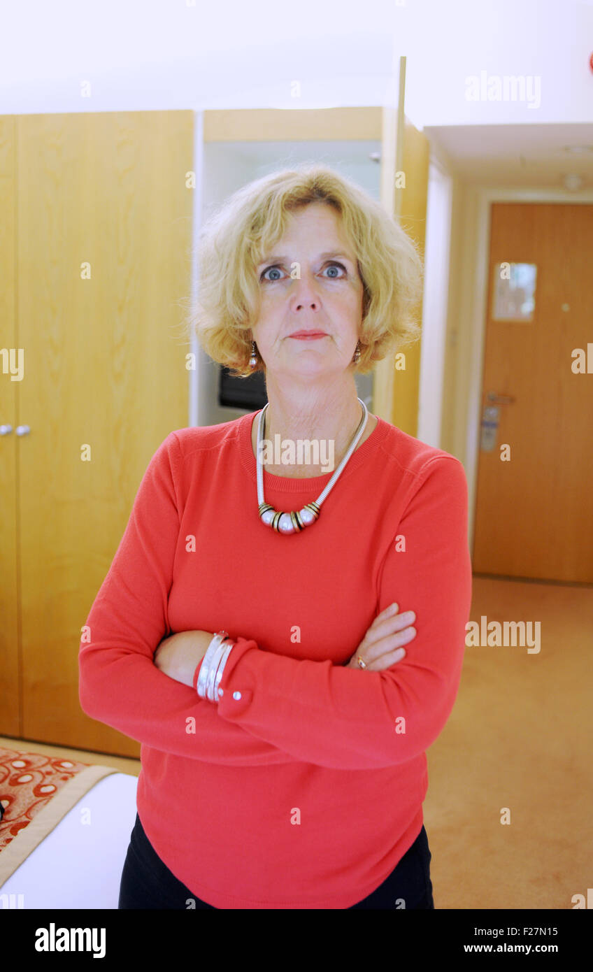 Applying Trägerin Koralle rosa farbigen Top und blauen Hosen auf streng Kamera mit verschränkten Armen Stockfoto