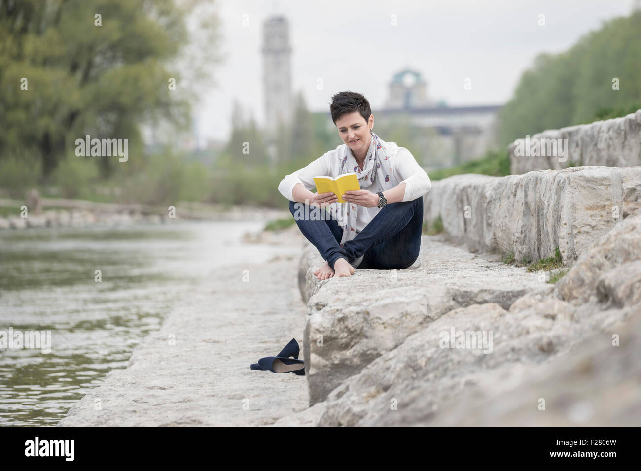 Reife Frau sitzen auf Stufen und lesen Buch, Bayern, Deutschland Stockfoto