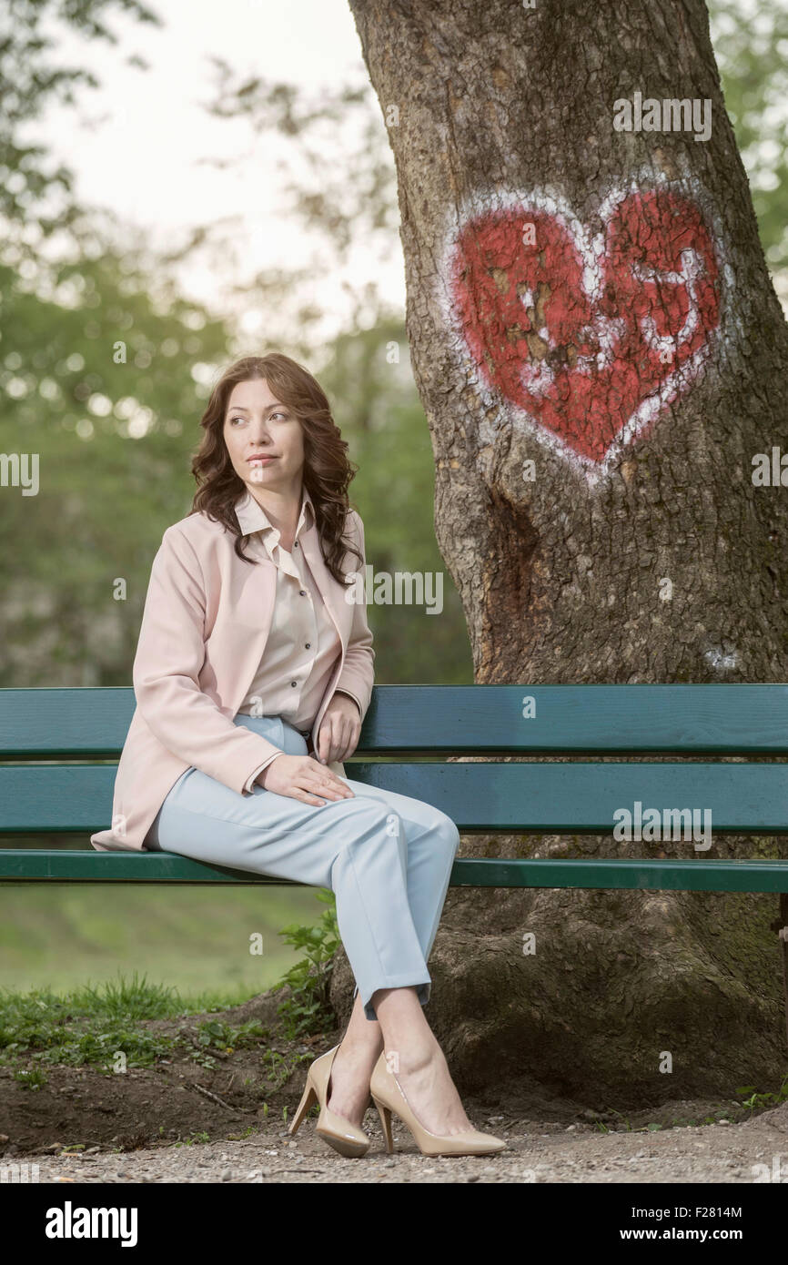 Reife Frau wartet auf ihr Date auf Park Bench, Bayern, Deutschland Stockfoto