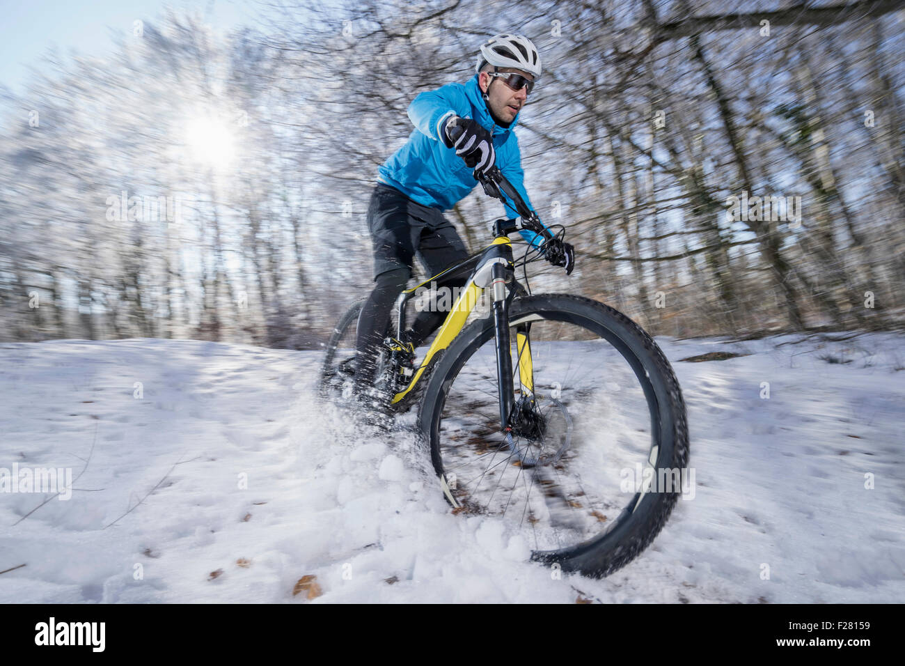 Mountainbiker, die mit dem Fahrrad in einem verschneiten Wald, Bayern, Deutschland Stockfoto