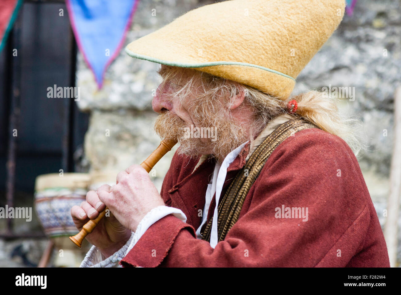 Mittelalterliche Re-enactment. Lebendige Geschichte. Ältere Erwachsene, buschige Seite - Verbrennungen und charaktervollen Gesicht, gekleidet wie Reisen, Minnesänger, spielen kurze Flöte. Stockfoto