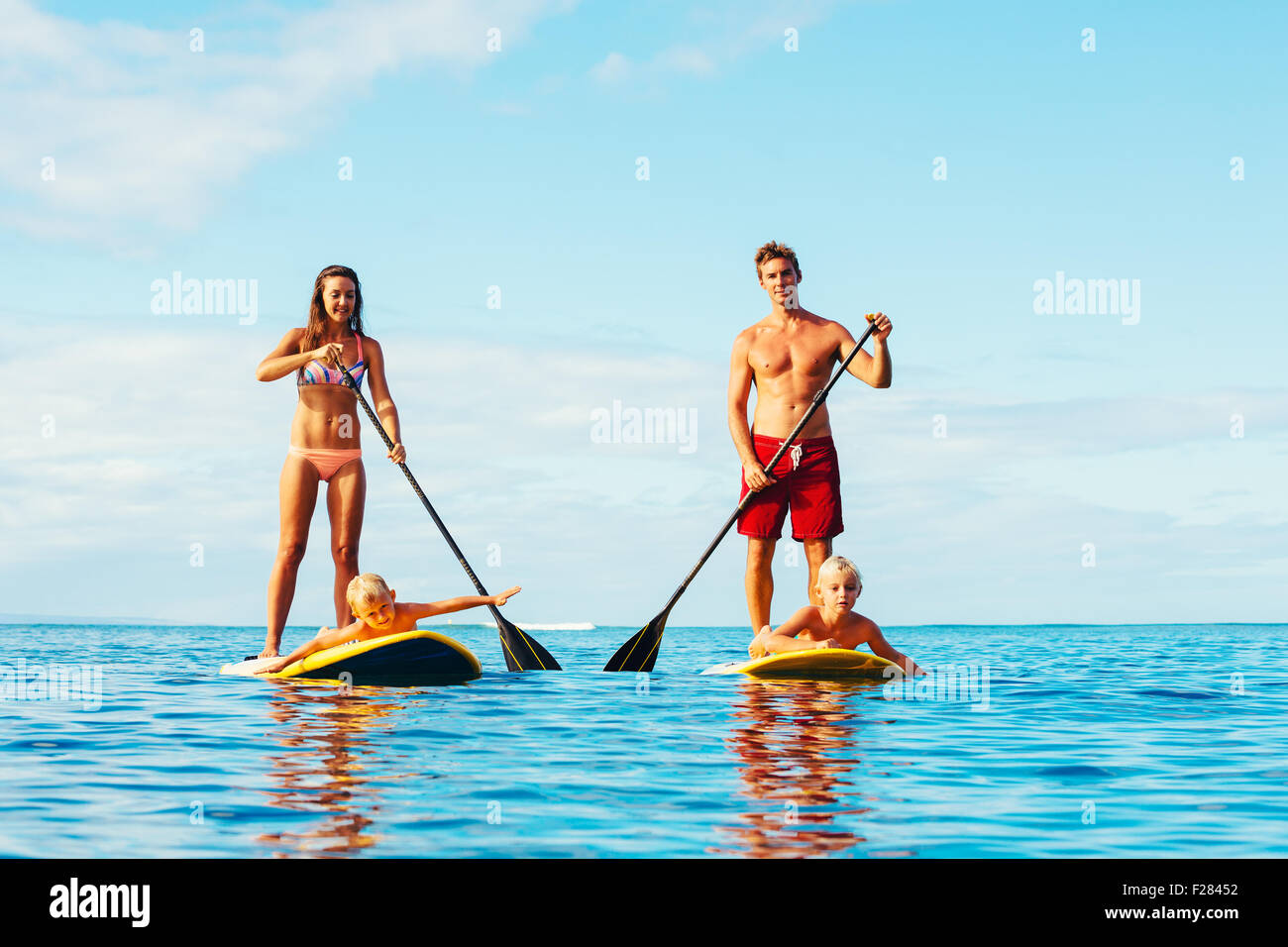 Familie mit Spaß Stand Up Paddling zusammen im Ozean an schönen sonnigen Morgen Stockfoto