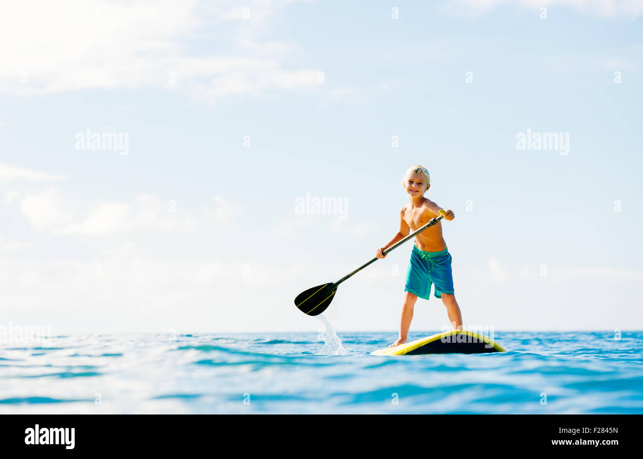 Kleiner Junge mit Spaß Stand Up Paddling in den Ozean Stockfoto