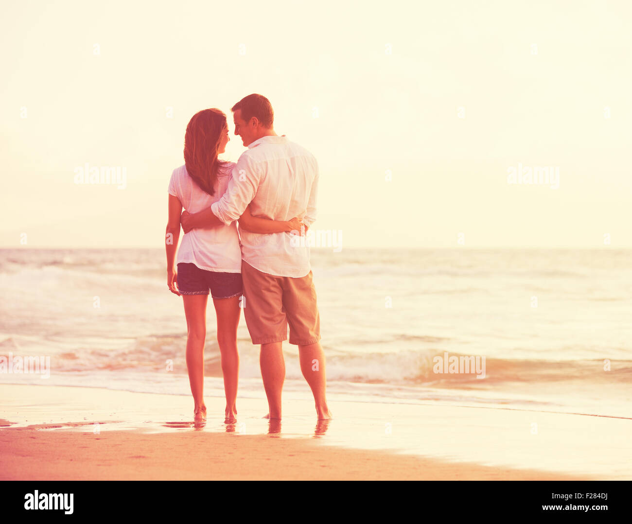 Romantisches Brautpaar schönen Sonnenuntergang am Strand genießen Stockfoto