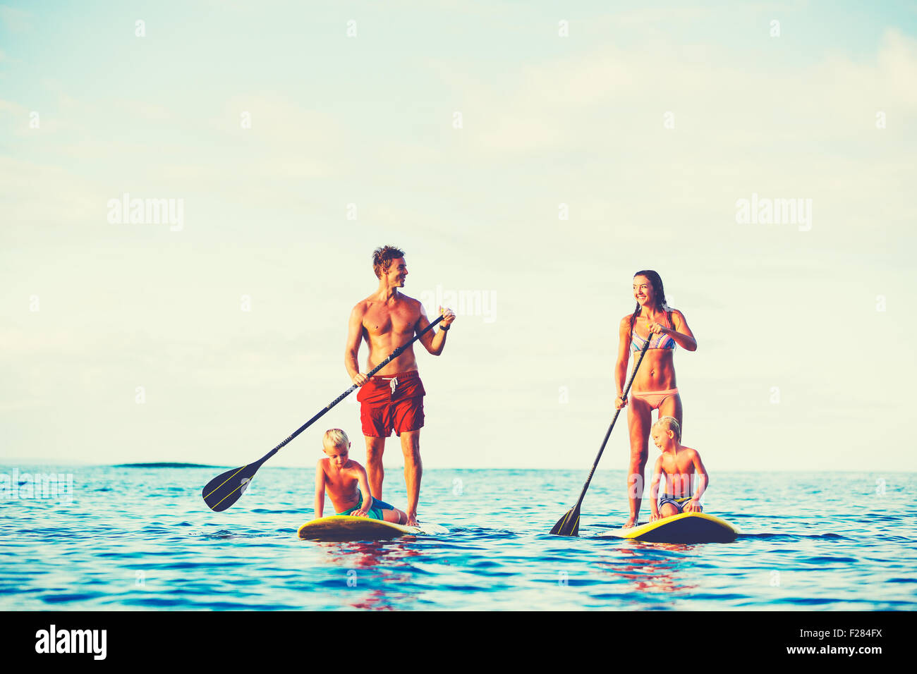 Familie mit Spaß Stand Up Paddling zusammen im Ozean an schönen sonnigen Morgen Stockfoto