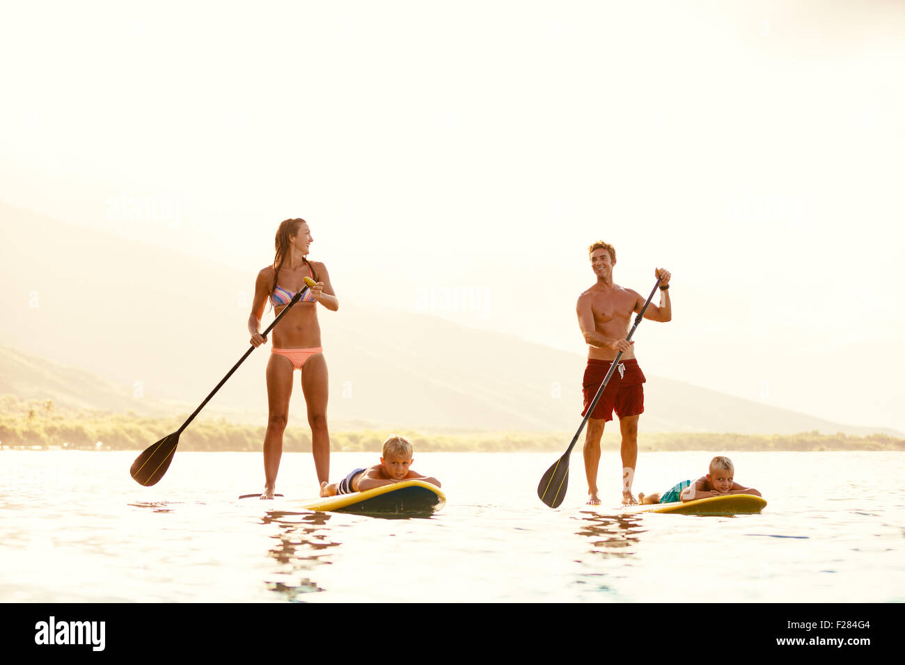Familie mit Spaß Stand Up Paddling zusammen im Ozean an schönen sonnigen Morgen Stockfoto