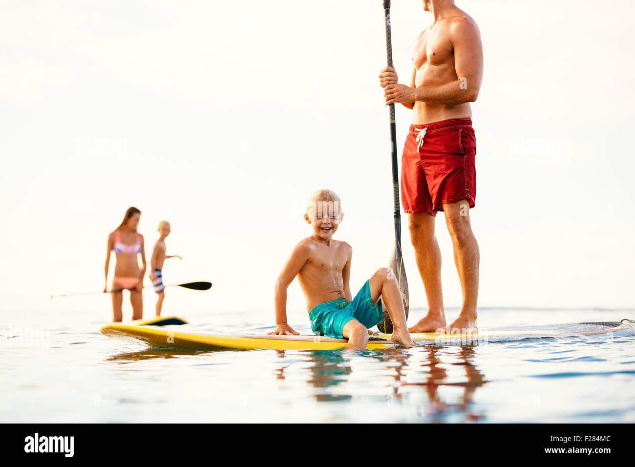 Familie mit Spaß Stand Up Paddling zusammen im Ozean an schönen sonnigen Morgen Stockfoto