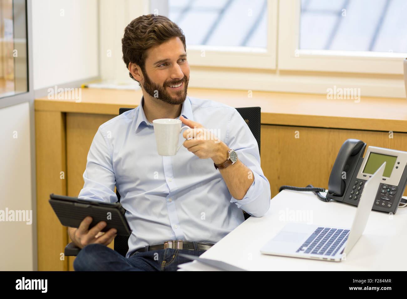 Porträt von lächelnden Geschäftsmann hält Kaffeetasse im Büro Stockfoto