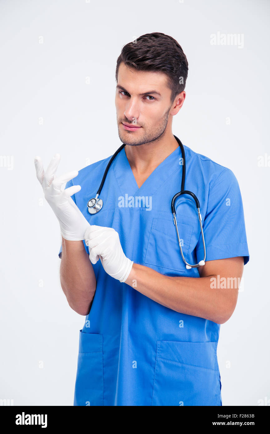 Porträt eines schönen männlichen Arztes setzen Handschuhe isoliert auf weißem Hintergrund Stockfoto