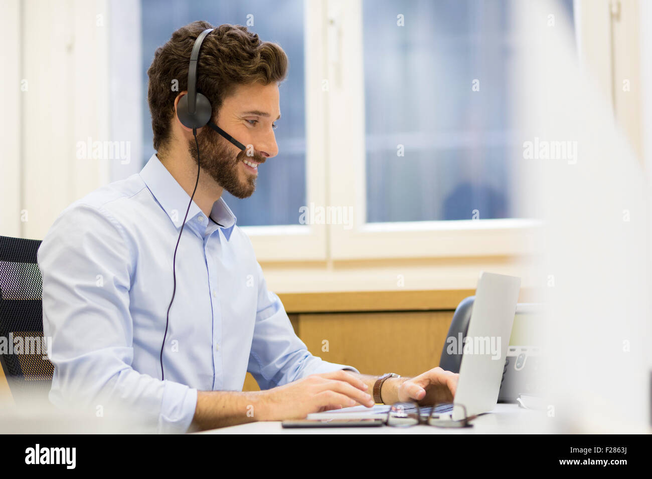 bärtiger Mann tragen Kopfhörer mit laptop Stockfoto